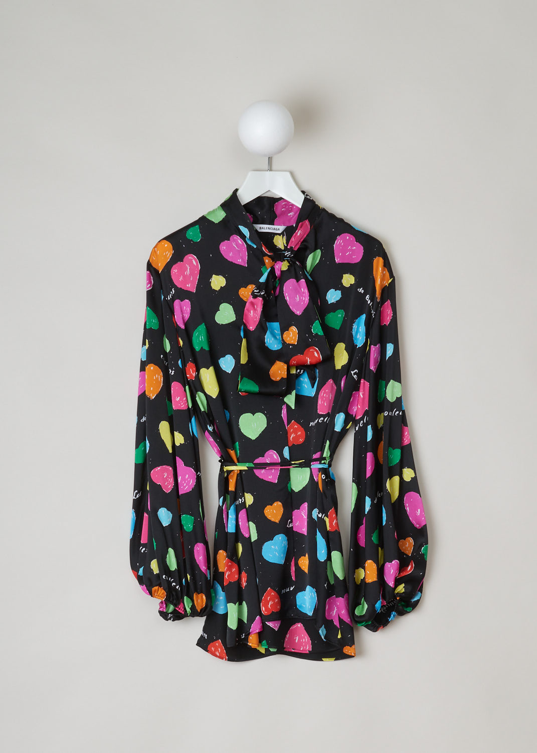 Balenciaga, Archive hearts print blouse, WL0_659088_TKL08_1000, black, pink, green, yellow, blue, print, front, This blouse features an archive hearts and text print which stands out against the black silk background. It has a self tie collar and a belted waist. The blouse also has long sleeves with elasticated cuffs. 
