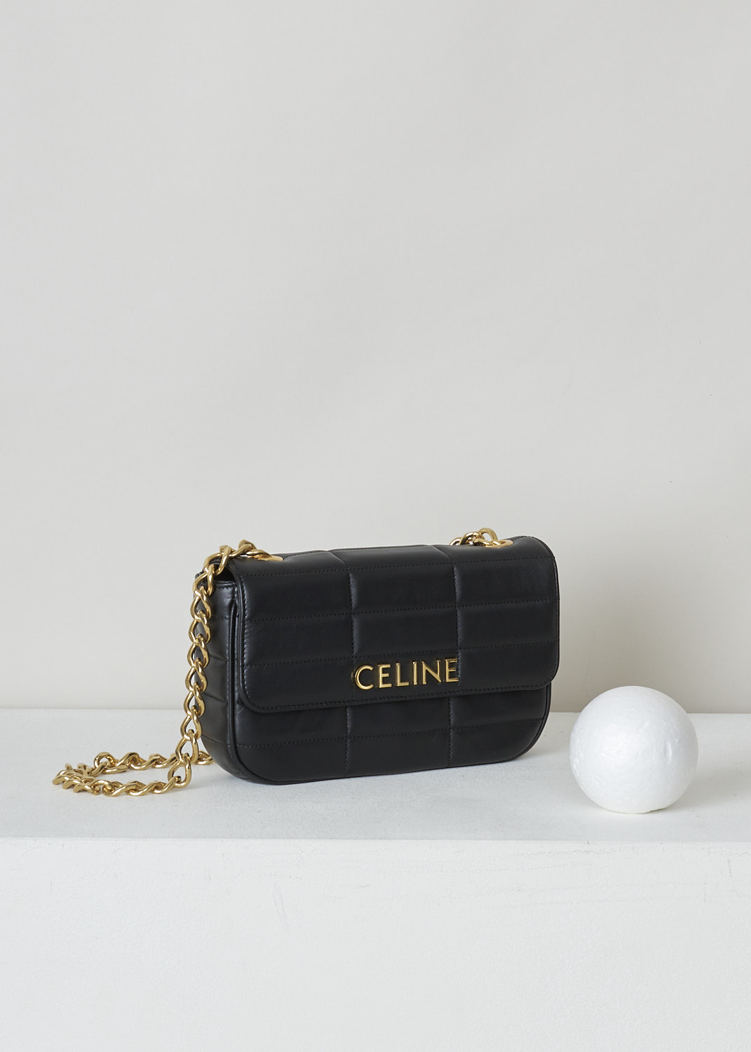 CELINE, BLACK MATELASSÃ‰ SHOULDER BAG WITH GOLD CHAIN, 111273EPZ_38NO, Black, Side, This black matelassÃ© shoulder bag has gold-tone metal hardware with the brand's lettering on the front and a gold chain shoulder strap. The bag has a snap button closure. The flap opens to the main compartment with a inner pocket to the backside


