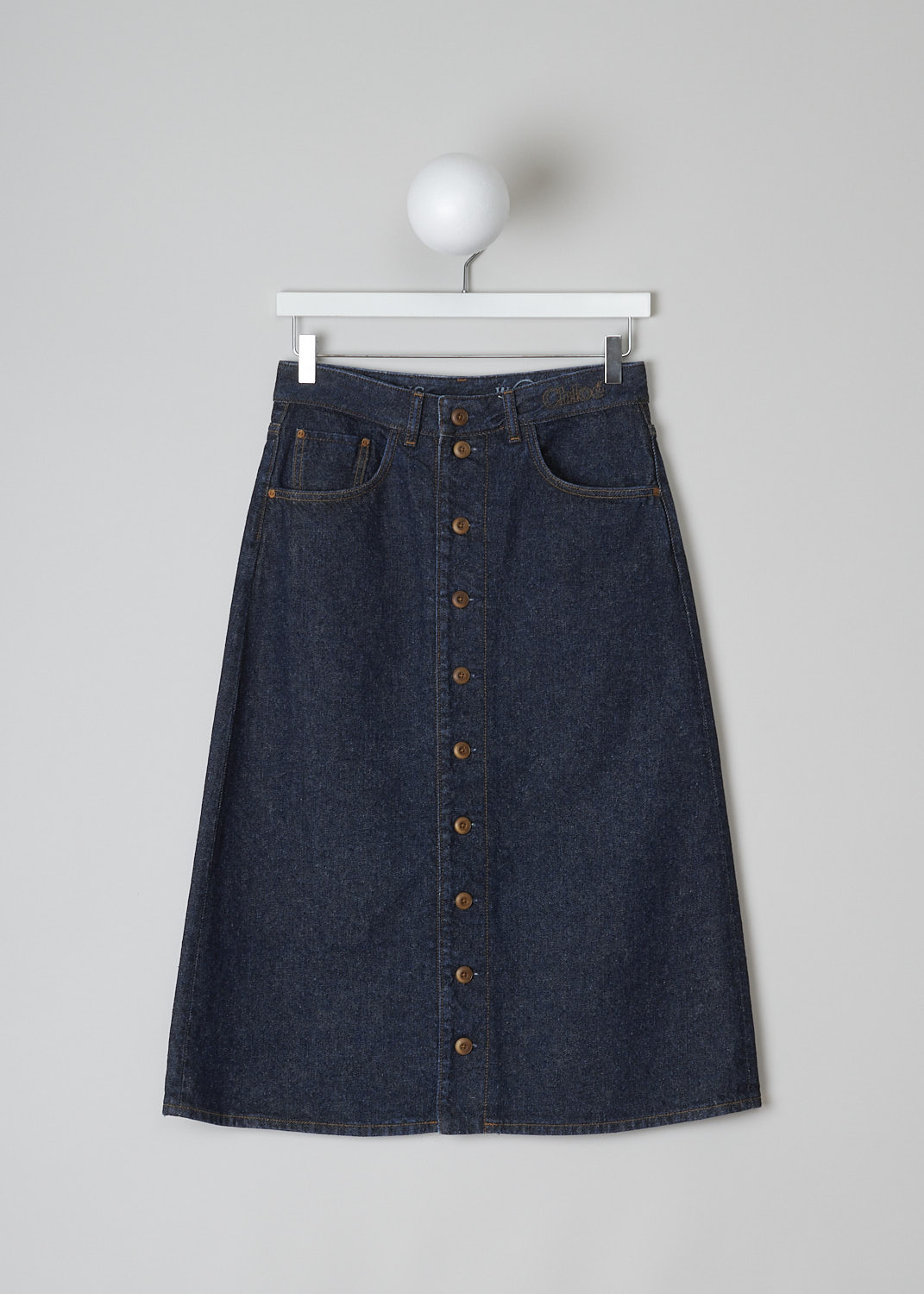 CHLOÃ‰, A-LINE DENIM MIDI SKIRT IN ICONIC NAVY, CHC22ADJ6615748A_SKIRT_ICONIC_NAVY, Blue, Front, This denim A-line midi skirt in Iconic Navy has a waistband with belt loops and the brand's logo embroidered on the front. The skirt has a front button closure. This skirt has a 5-pocket design, with two slanted pockets and a coin pocket in the front and two patch pockets in the back.  

