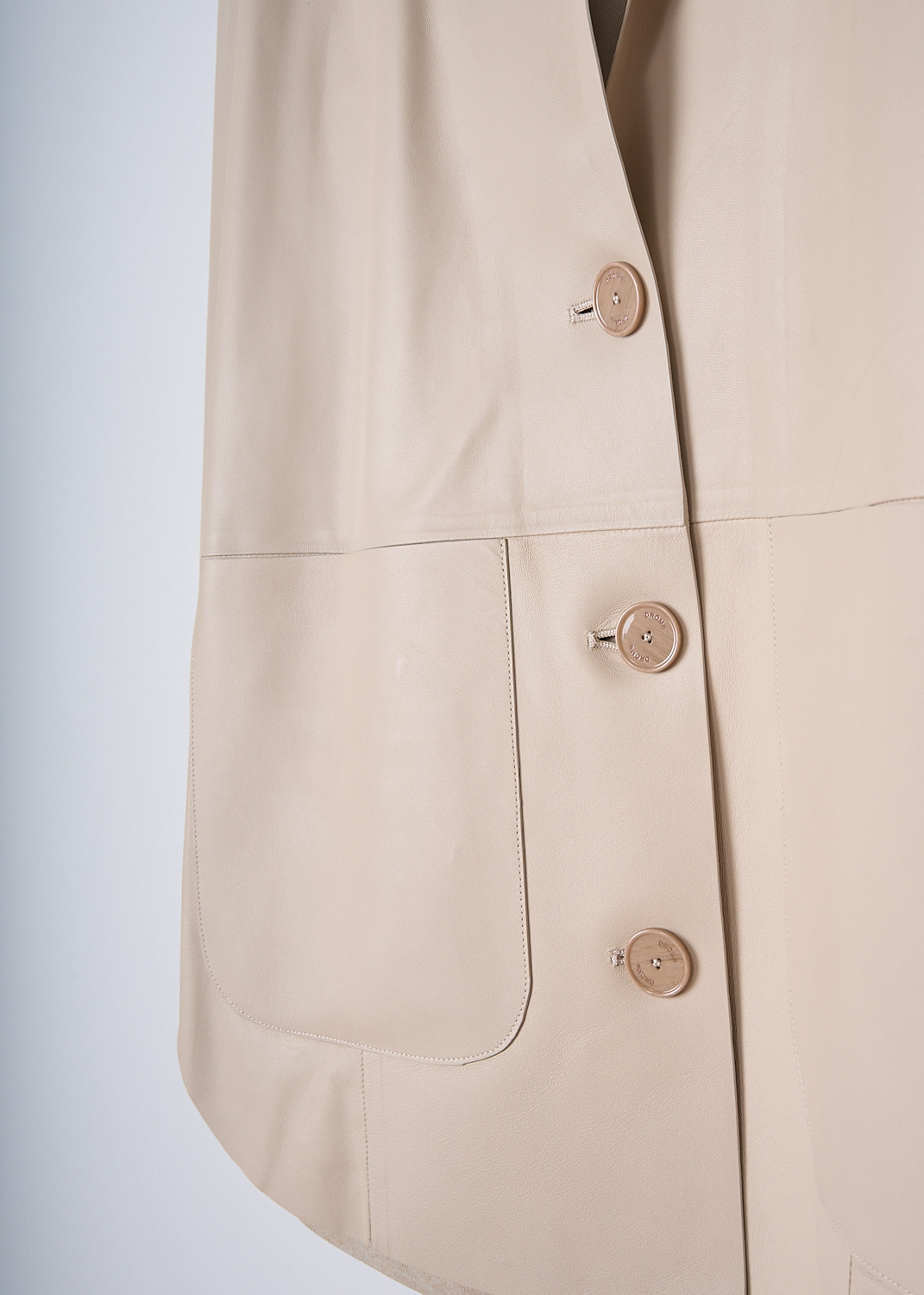 DROME, BOXY BEIGE LEATHER JACKET, DPD3112V_D400_B363, Beige, Detail, This single-breasted beige leather jacket has a notched lapel and a front button closure. The jacket has a boxy silhouette. On the front, the jacket has two patch pockets. The jacket has a rounded hemline. 

