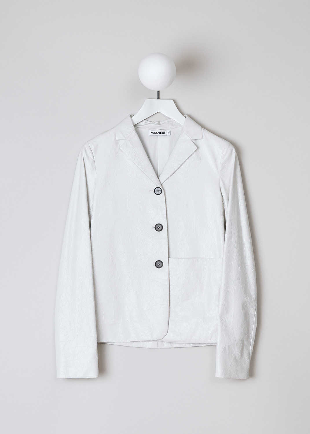 JIL SANDER, CROPPED WHITE CRACKLED LEATHER JACKET, JSPN651570_WNL00080_105, White, Front, This cropped jacket is made of a crackled white leather. The jacket has a notched lapel and a front button closure with black buttons. In the front, the jacket has a single patch pocket to one side. The jacket has a straight hemline. 

