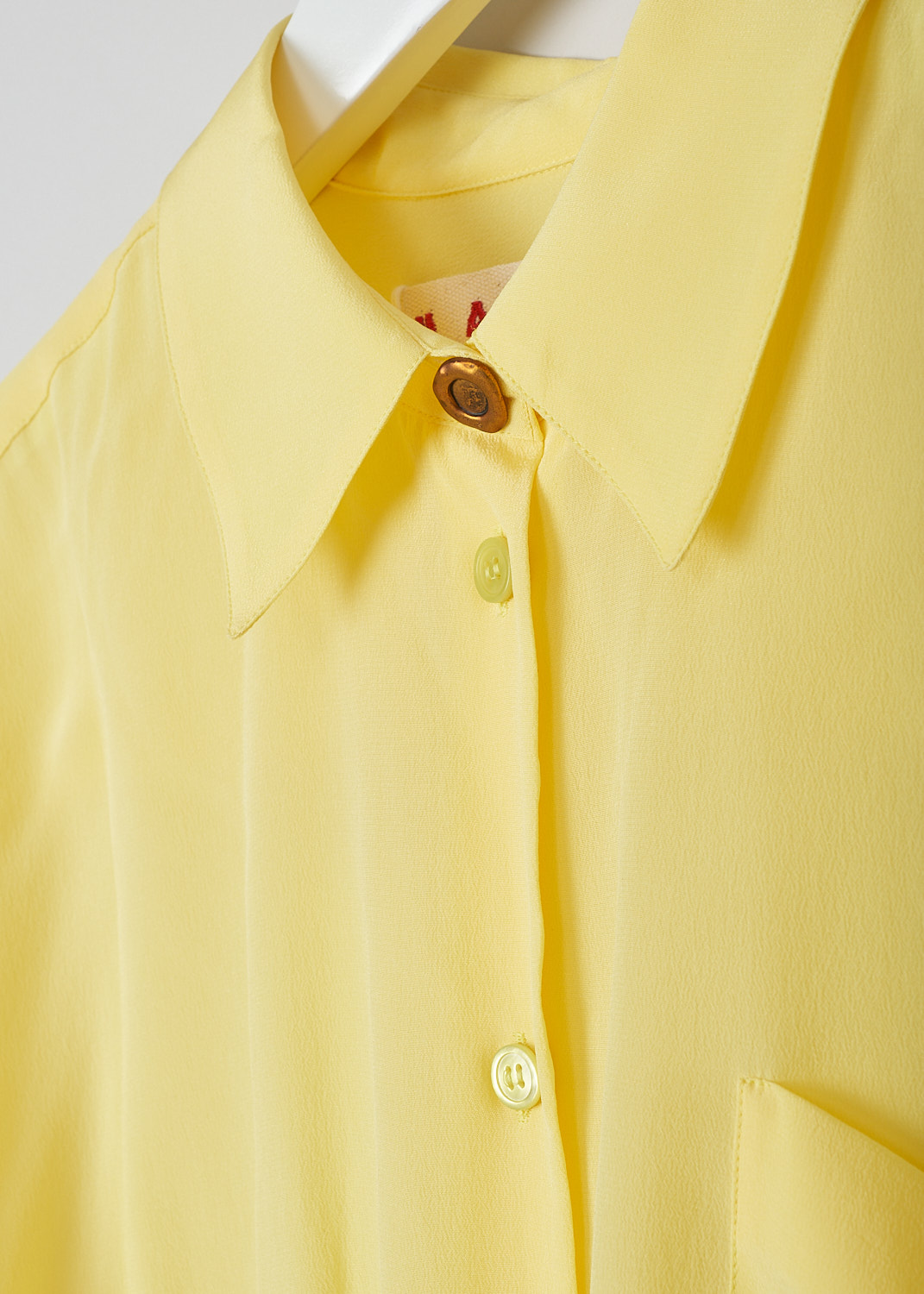 MARNI, LEMON YELLOW SILK CRÊPE DE CHINE BLOUSE, CAMA0526A0_UTSF72_00Y20, Yellow, Detail, This cropped silk crêpe de Chine blouse in lemon yellow has a pointed collar and a front button closure, with a bronze-colored top button. The long sleeves cuffs with those same bronze-colored buttons. In the front, the blouse has a single breast pocket. The hemline has a drawstring. 
  

