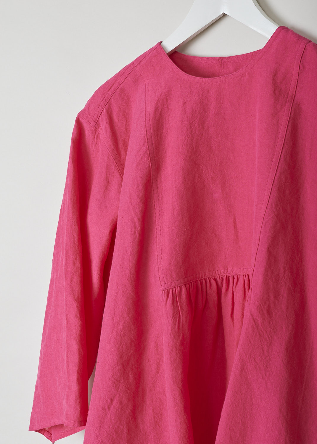 SOFIE Dâ€™HOORE, FUCHSIA COLORED BINETTE TOP, BINETTE_LIFE_FUCHSIA, Pink, Detail, This oversized fuchsia top features a round neckline, dropped shoulders and long sleeves. The A-line top has a square bib-like front with pleated details below. Concealed in the side seams, slanted pockets can be found. The top has an asymmetrical finish, meaning the back is a little longer than the front. 

