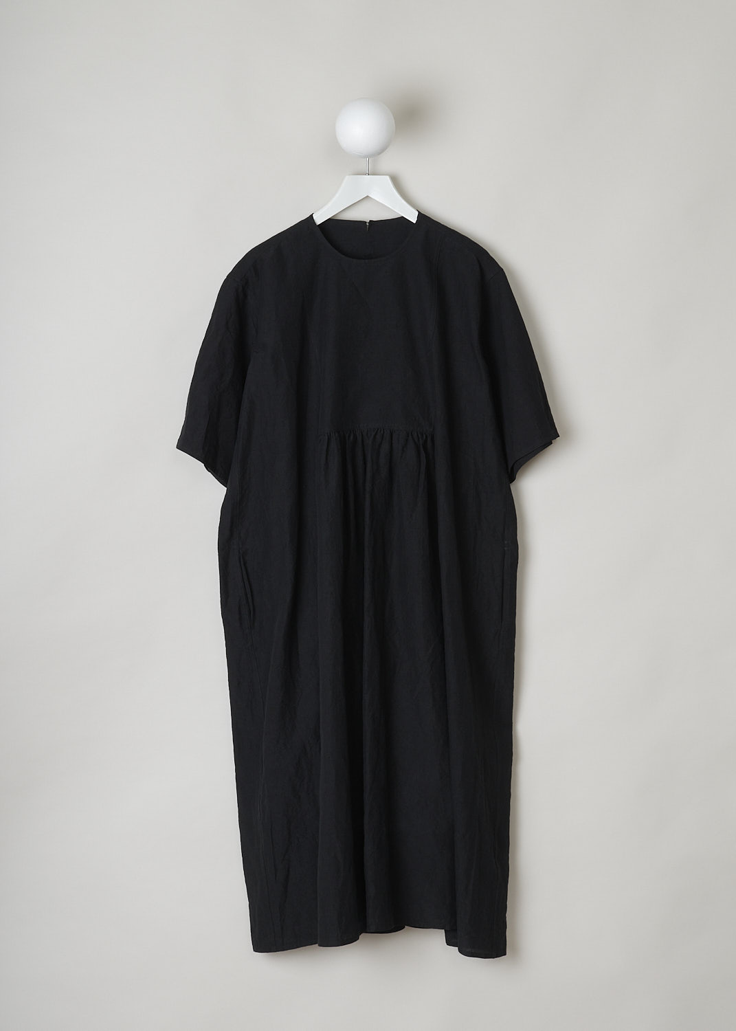 SOFIE Dâ€™HOORE, BLACK LINEN DARNELLE DRESS, DARNELLE_LIFE_BLACK, Black, Front, This oversized black midi dress features a round neckline, dropped shoulders and short sleeves. The A-line dress has a square bib-like front with pleated details below. Concealed in the side seams, slanted pockets can be found. The dress has a straight hemline with slits on either side. 

