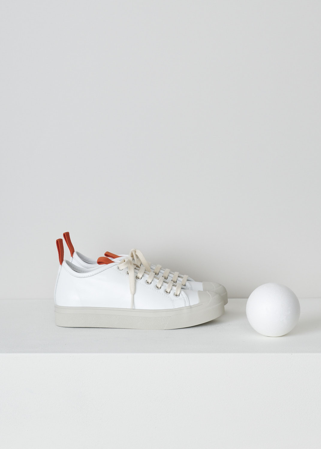SOFIE Dâ€™HOORE, WHITE LEATHER SNEAKERS WITH RED ACCENTS, FABLE_LCOL_WHCL, White, Side, These white leather sneakers feature a front lace-up closure with white laces. Red pull-tabs can be found on the back of the heel and on the front of the tongue. These sneakers have a round toe with a beige rubber toe cap that goes down into the rubber sole in that same beige color. 

