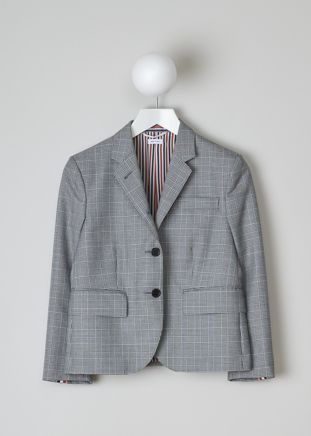 THOM BROWNE, BLACK AND WHITE CHECK SPORT JACKET, FBC010A_25057_980, Black, White, Front, This single-breasted sport jacket has a black and white houndstooth check motif. The jacket has a notched lapel and a front button closure. In the front, the jacket has a single breast pocket and two flap welt pockets. On the inside, the jacket has a striped lining, three inner pockets and a name tag. The brand's signature striped grosgrain loop tab can be found in the back. The jacket has a double vent.  
