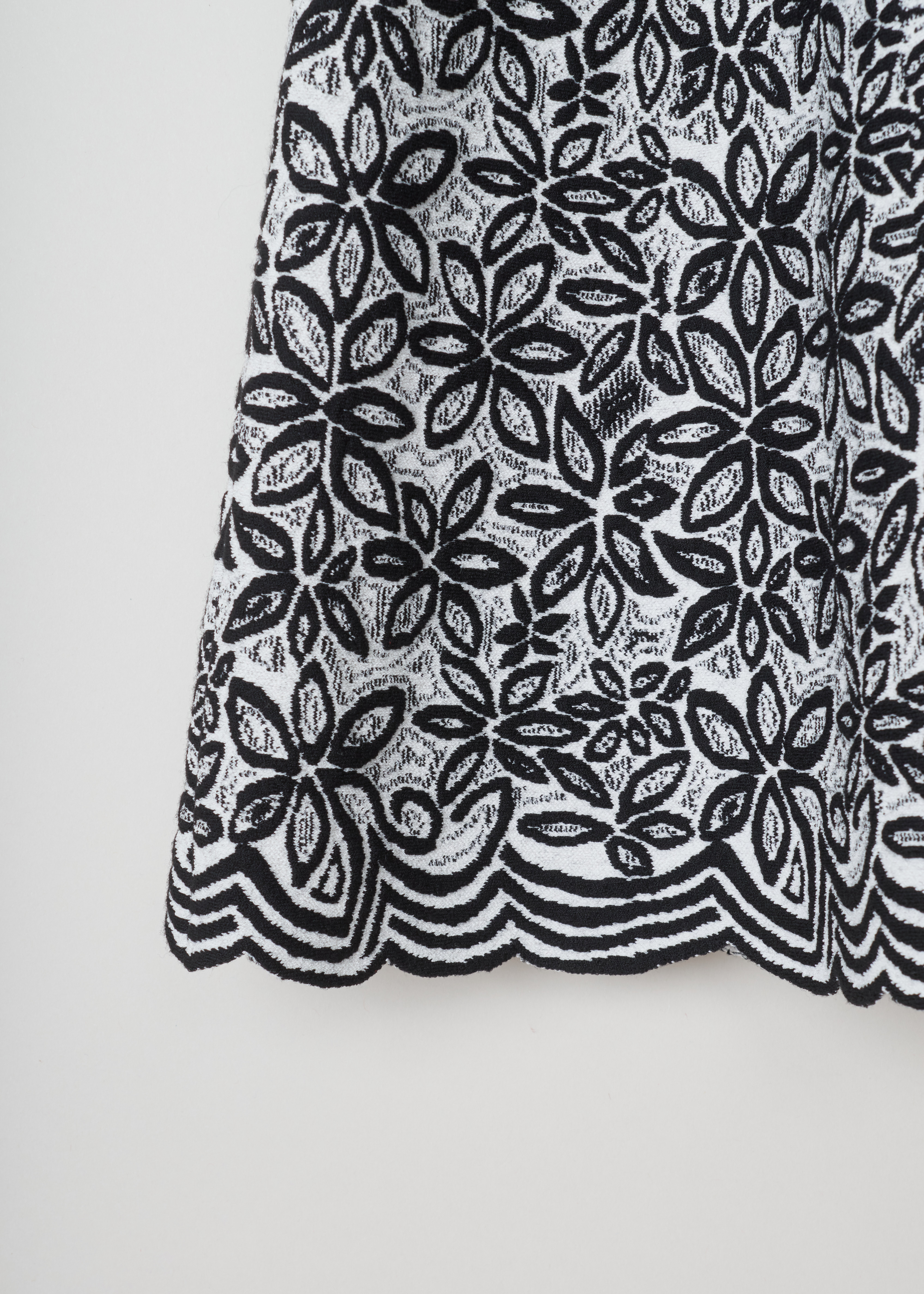 Alaïa, Wool-blend tunic with a flower pattern, 7W9UE52RM353_TUNIQUE_ADENIUM_C009_Blanc/Noir, Grey, Print, Detail 1, Jacquard knitted tunic with a black and white flower motif. The dress has short sleeves, a wide round neckline, an A-line silhouette and scalloped hems.

