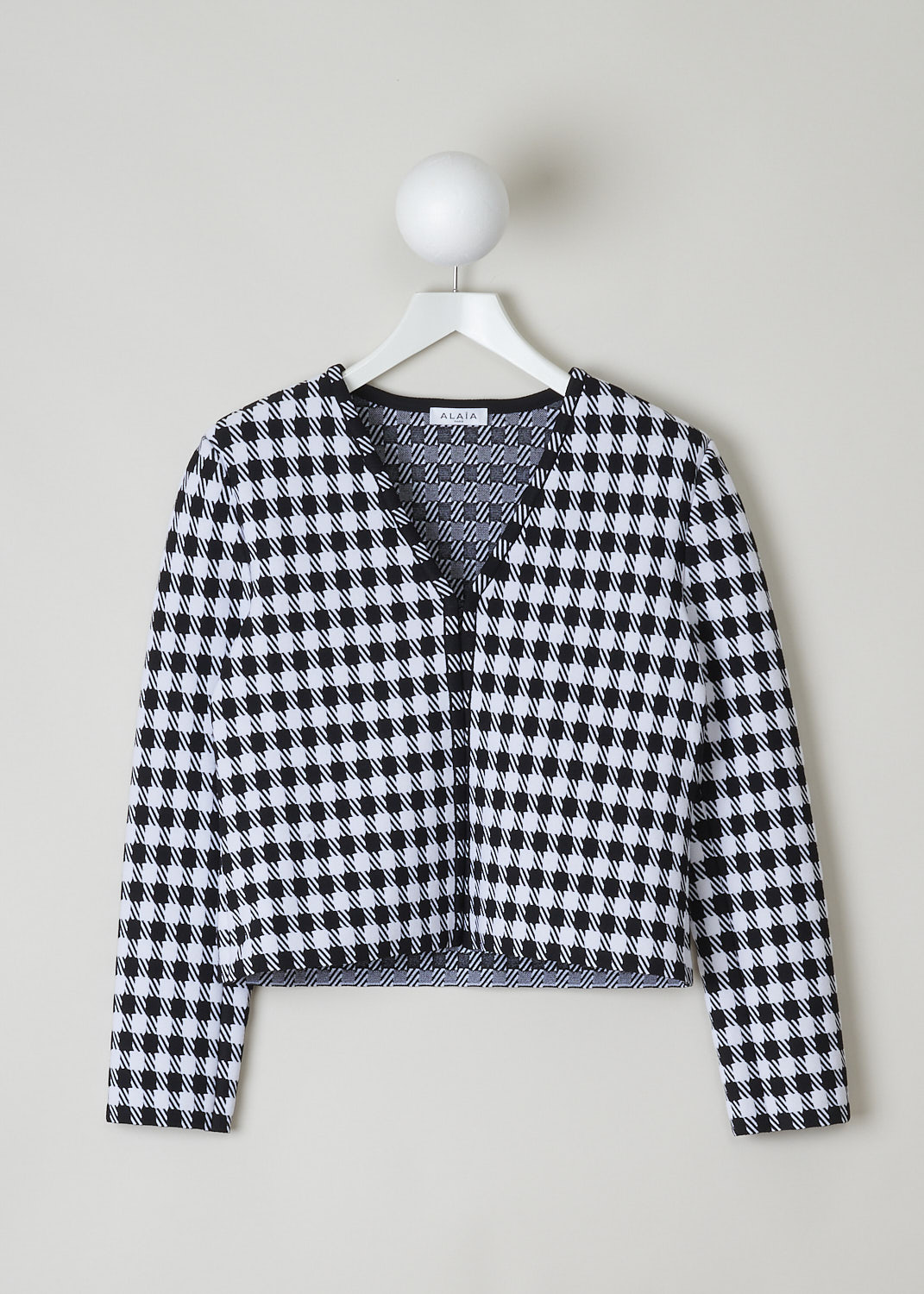 ALAÏA, CROPPED HOUNDSTOOTH PRINTED JACKET, AA9V10432M710_HOUNDSTOOTH_991, Black, White, Print, Front, This long sleeve jacket has a magnified black and white Houndstooth print throughout. The jacket has a cropped length, with the hem falling to the hip. The jacket has an open front with just a single hook-closure on the V-necks end. The jacket has shoulder pads.


