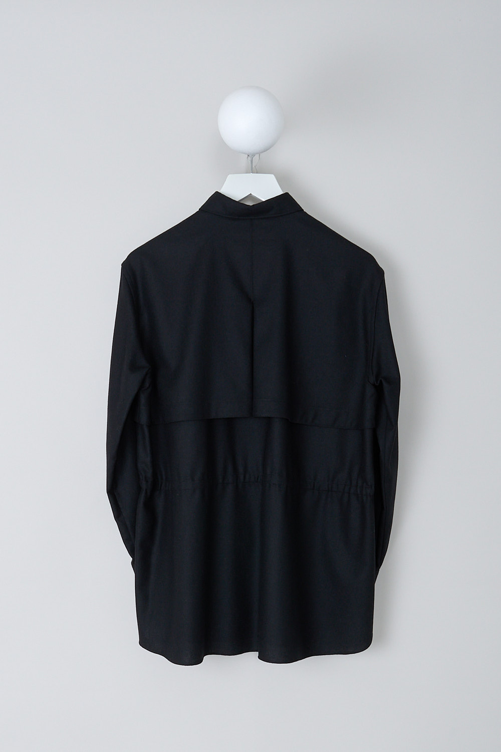 ASPESI, BLACK BLOUSE WITH DRAWSTRING DETAIL, 5457_L629_01241, Black, Back, This black blouse has a classic collar and a button placket in the front. The long sleeves have buttoned cuffs. The blouse has a storm shield across the chest that extends to the back. A drawstring can be used to cinch in the waist. The blouse has a curved hemline.
