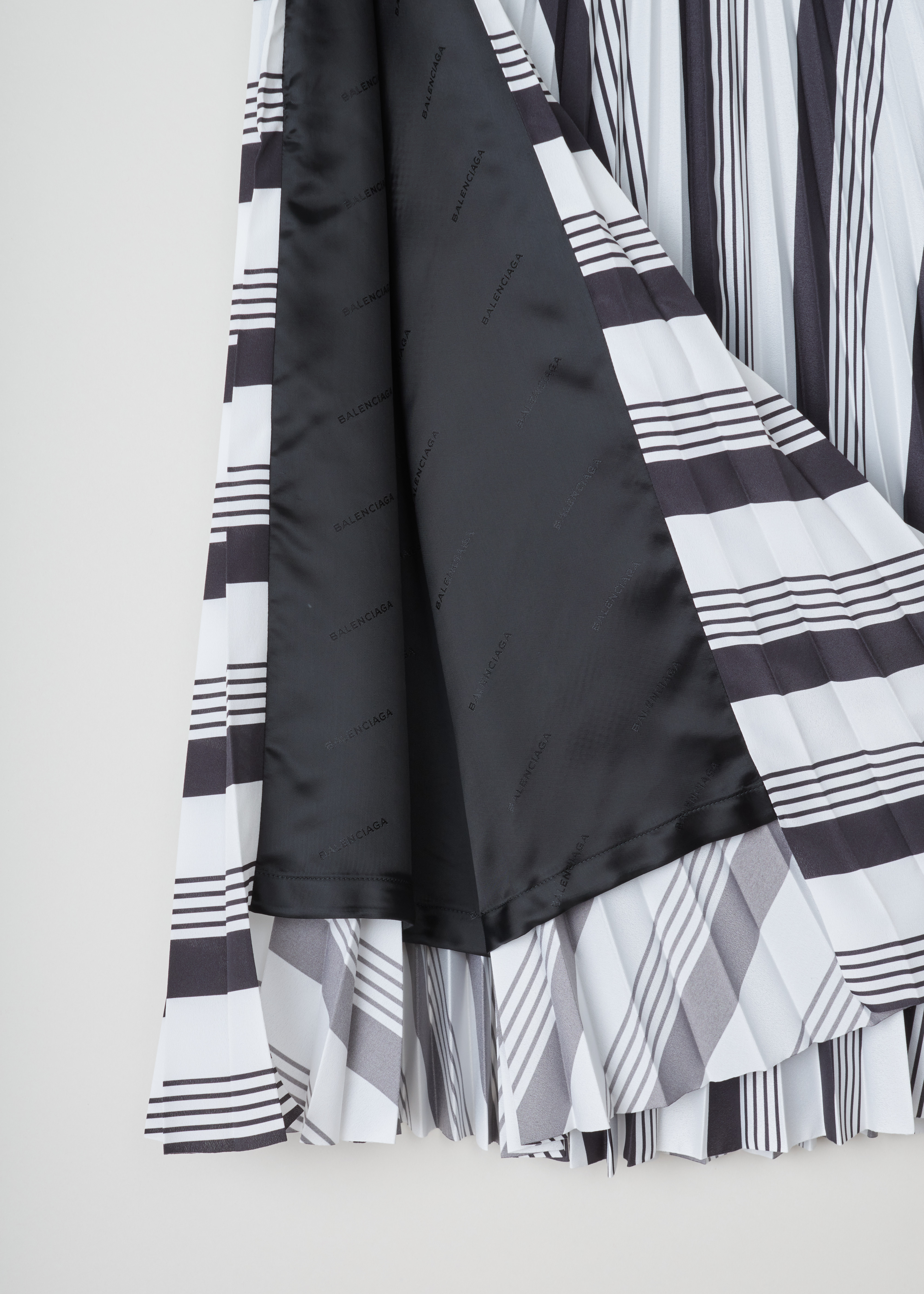 Balenciaga Striped pleated skirt 501971_TYA43_1070 noir blanc detail. White plissÃ© skirt with curved black stripe pattern, small waistband with four belt hoops, invisible zipper and slit on the side.