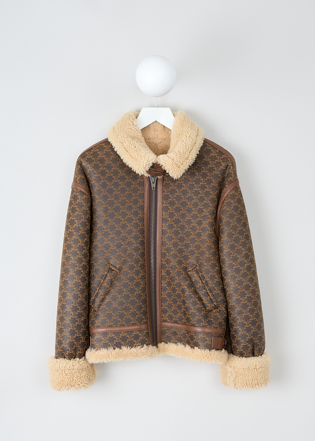 Celine, Monogram-print shearling bomber, 2E915_1480_01CZ, Brown, Print, Front, This shearling-trimmed bomber has a monogram logo-print throughout. The jacket has a double-belted shearling collar and a front zip closure. Side slanted pockets can be found on the front. Brown leather trims decorated the sleeves and back. The long sleeves have shearling cuff tabs. The jacket has a shearling lined hemline. The jacket is fully lined with shearling. 
