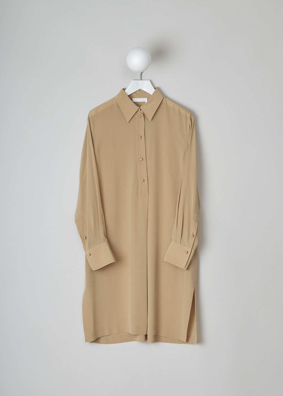 CHLOÉ, PEARL BEIGE SILK SHIRT DRESS, CHC22URO64004278, Beige, Front, This pearl beige silk dress has a classic collar and a button placket with round ceramic buttons that go halfway across the chest. Below the placket, a single knife pleats goes down to the hemline. This loose fitted dress has long sleeves with buttoned cuffs. Slanted pockets are concealed in the side seam. The dress has side slits and an asymmetrical finish, meaning the back is a little longer than the front. A centre box pleat runs vertically down the back.
