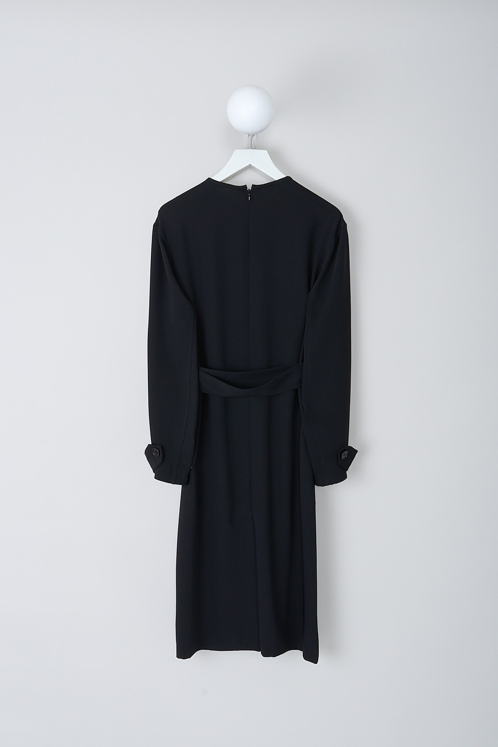 DRIES VAN NOTEN, BLACK LONG SLEEVE DOSANA DRESS, DOSANA_7364_WW_DRESS_BLACK, Black, Back, This black Dosana dress has a high round neckline. The dress has a storm flap detail on the right shoulder. The long sleeves have buttoned sleeve straps on the cuffs. A detachable fabric belt with a metal buckle can be used to cinch in the waist. The dress has slanted pockets with a buttoned flap. In the back, a concealed centre zip functions as the closure. A centre slit can be found both in the front and back. The dress has a straight hemline. 
