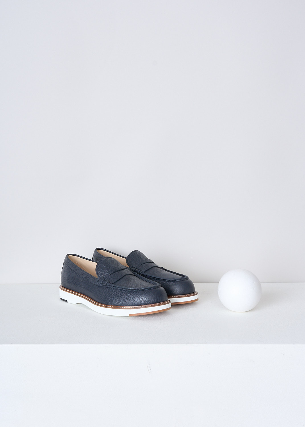 TODS, DARK BLUE GRAINED LEATHER PENNY LOAFERS, XXW05E0EB60EK0U801, Blue, Front, These dark blue grained leather penny loafers have a almond toe and a decorative slotted leather strip over the upper side. The loafers have white soles with a beige trim and light stitching. The brand's logo has been subtly embossed on the front


