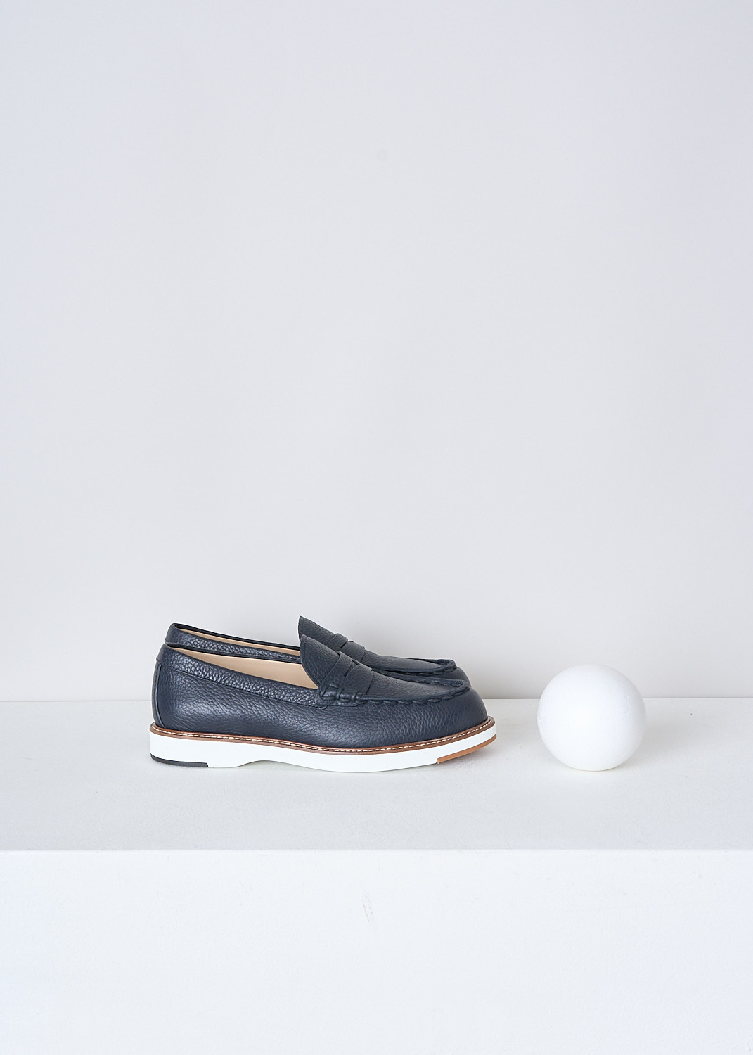 TODS, DARK BLUE GRAINED LEATHER PENNY LOAFERS, XXW05E0EB60EK0U801, Blue, Side, These dark blue grained leather penny loafers have a almond toe and a decorative slotted leather strip over the upper side. The loafers have white soles with a beige trim and light stitching. The brand's logo has been subtly embossed on the front


