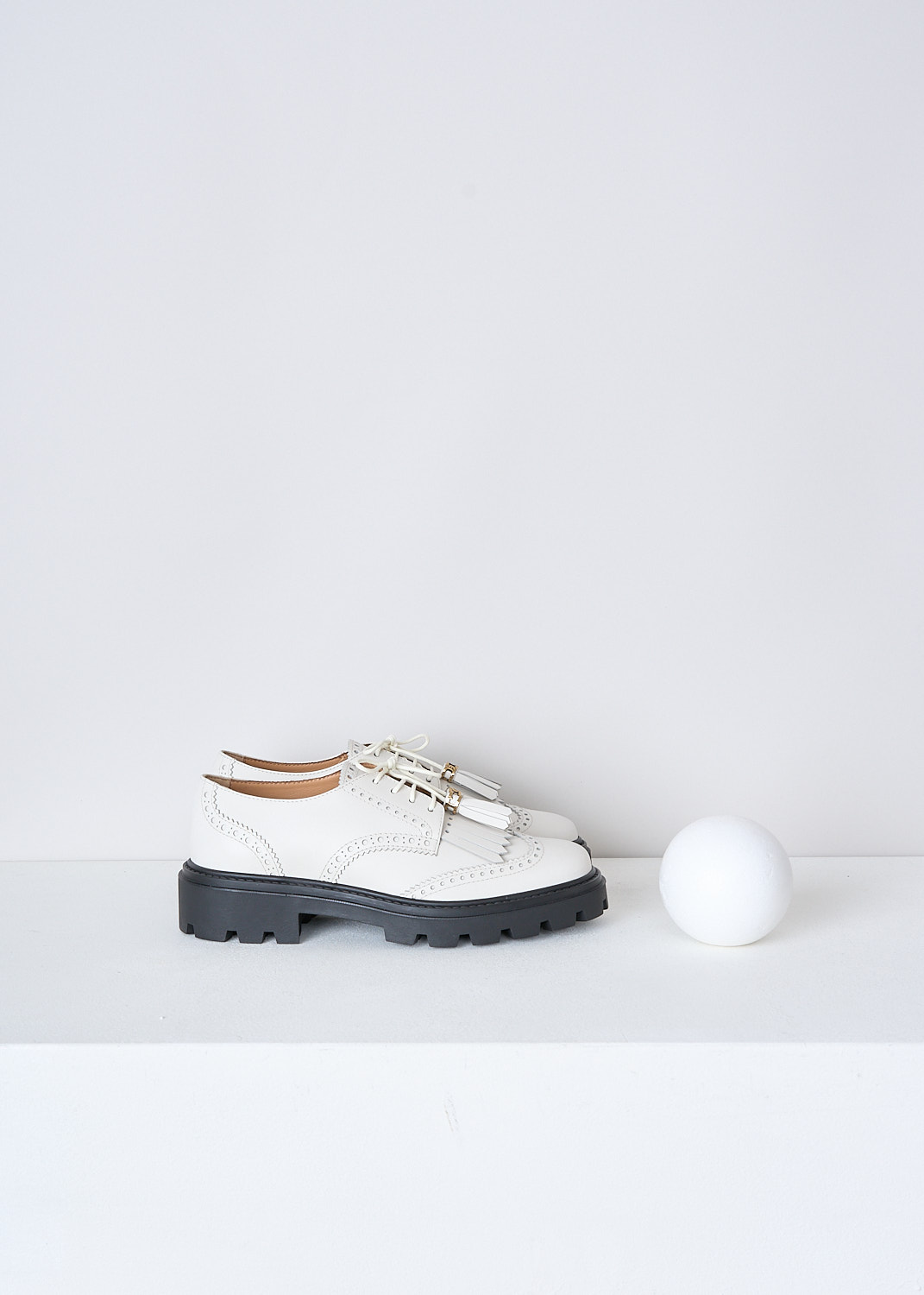 TODS, OFF-WHITE LOAFERS WITH TASSELS, XXW08J0HO10RBTB015, White, Side, These off-white leather derby shoes have a front lace-up closure. The off-white laces have tasseled tips. These shoes have a round toe with fringes across the vamp. Classic perforation detailing extends along the entire shoe. These shoes have a ridged black sole.


