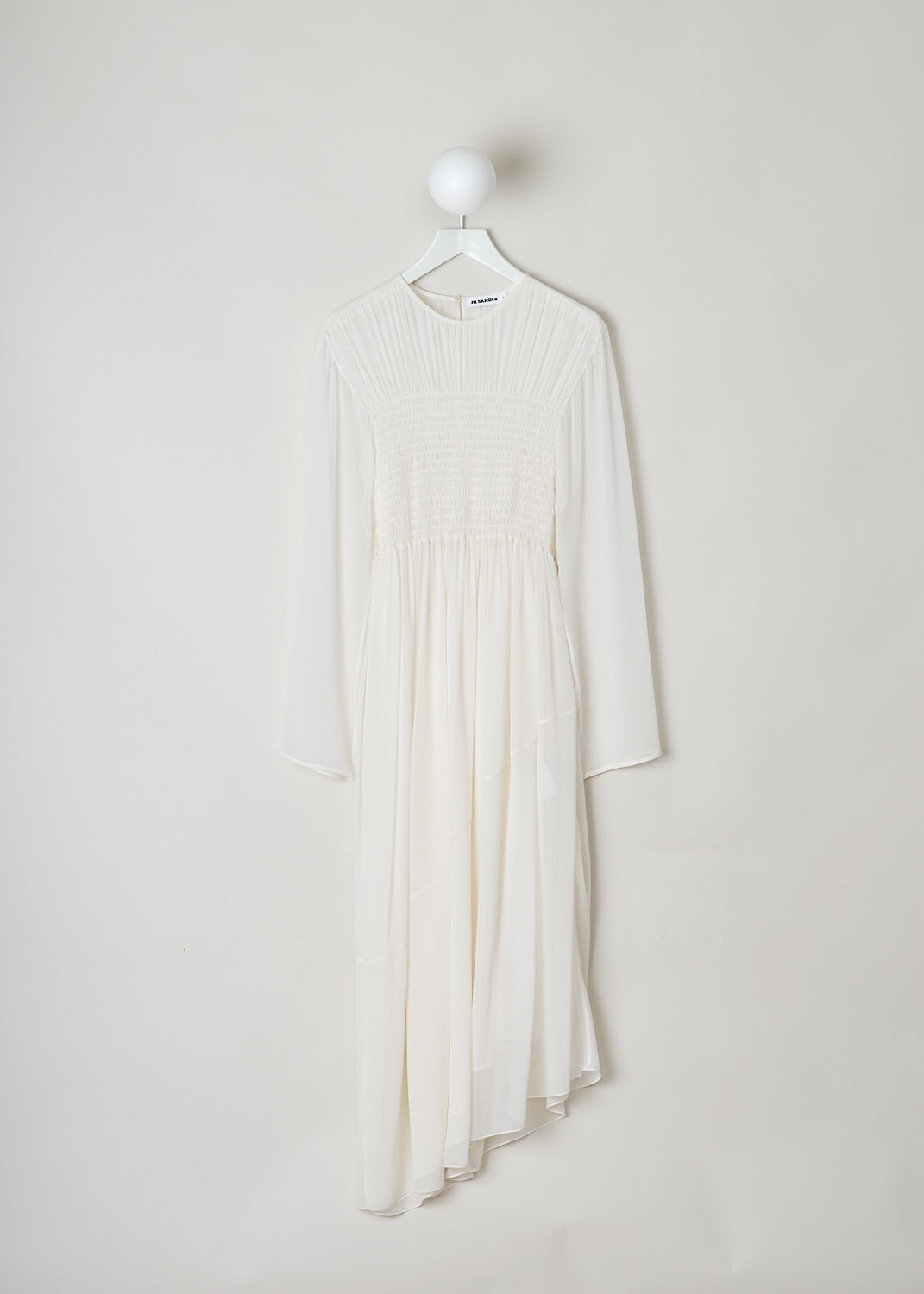 JIL SANDER, WHITE DRESS WITH SHIRRED BODICE, White, Front, This white long sleeve dress has pleats across the chest and a shirred bodice. The dress is made in a semi sheer fabric.  The skirt flows out from small crystal pleats. The hemline has an asymmetric finish, meaning that from left to right one side is longer than the other. A single button can be found in the back of the neck.
