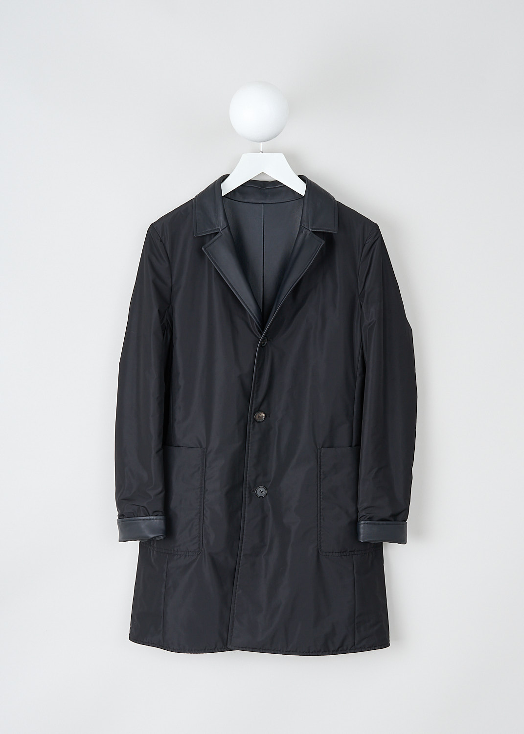 Jil Sander, Reversible dark blue Santander coat, SANTANDER_REV_L_NW6519076_WL562101A_402_DARK_BLUE, Blue, Front 1, This reversible dark blue Santander coat has a notched lapel and a front button closure. The long sleeves have a straight hem. The coat is reversible, with navy blue leather to one side and black polyester to the other side. On the leather side, the coat has slanted pockets. On the polyester side, the coat has patch pockets.  
