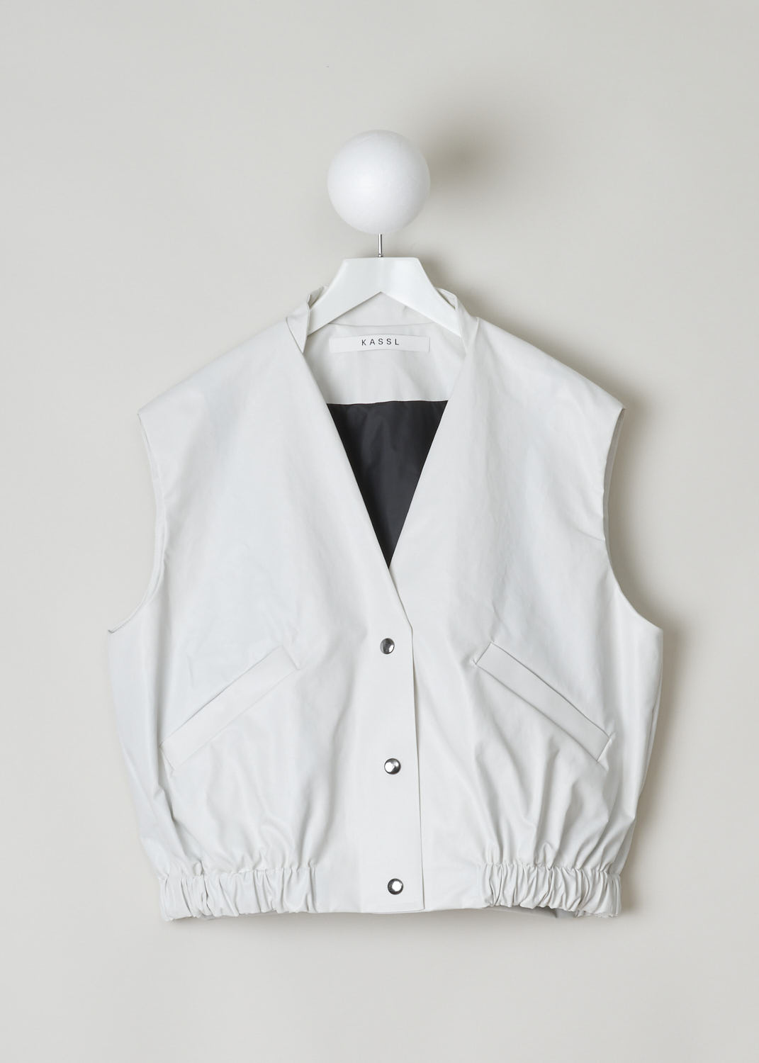 KASSL, SLEEVELESS BOMBER IN OFF WHITE, C212100000W, White, Front, This white sleeveless bomber features a front press button closure, a V-neckline and a gathered, elasticated waistline.  The bomber has two welt pockets with press button in the front and has two inner pockets. In the back of the neck a little loop can be found with which you can hang this garment. 
