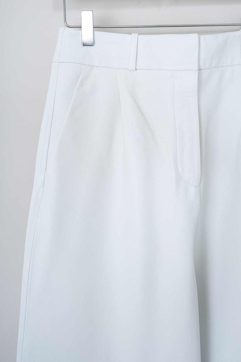 KASSL, WHITE LEATHER PANTS, R01230000W_RTW_TROUSERS_SOFT_LEATHER_WHITE, White, Detail, These high-waisted white leather pants have a waistband with belt loops and a concealed clasp and zip closure. In the front, these pants have slanted front pockets. The straight pant legs have a decorative seam at knee-hight and a straight hemline. In the back, the pants have welt pockets.   
