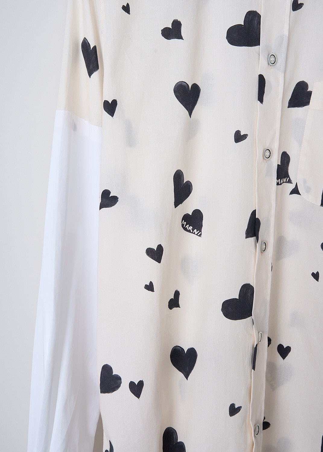 MARNI, BUNCH OF HEARTS POPLIN BLOUSE, CAMA0544QS_UTC280_BHW03, Black, White, Print, Detail, This Bunch of Hearts poplin blouse in stone white has an all-over heart print. The blouse has a spread collar, a front button closure and a single breast pocket. The long crisp white sleeves have buttoned cuffs. The brand's logo is embroidered in black on the back of the neck. The rounded hemline has an asymmetric finish, with the back being slightly longer than the back. 
