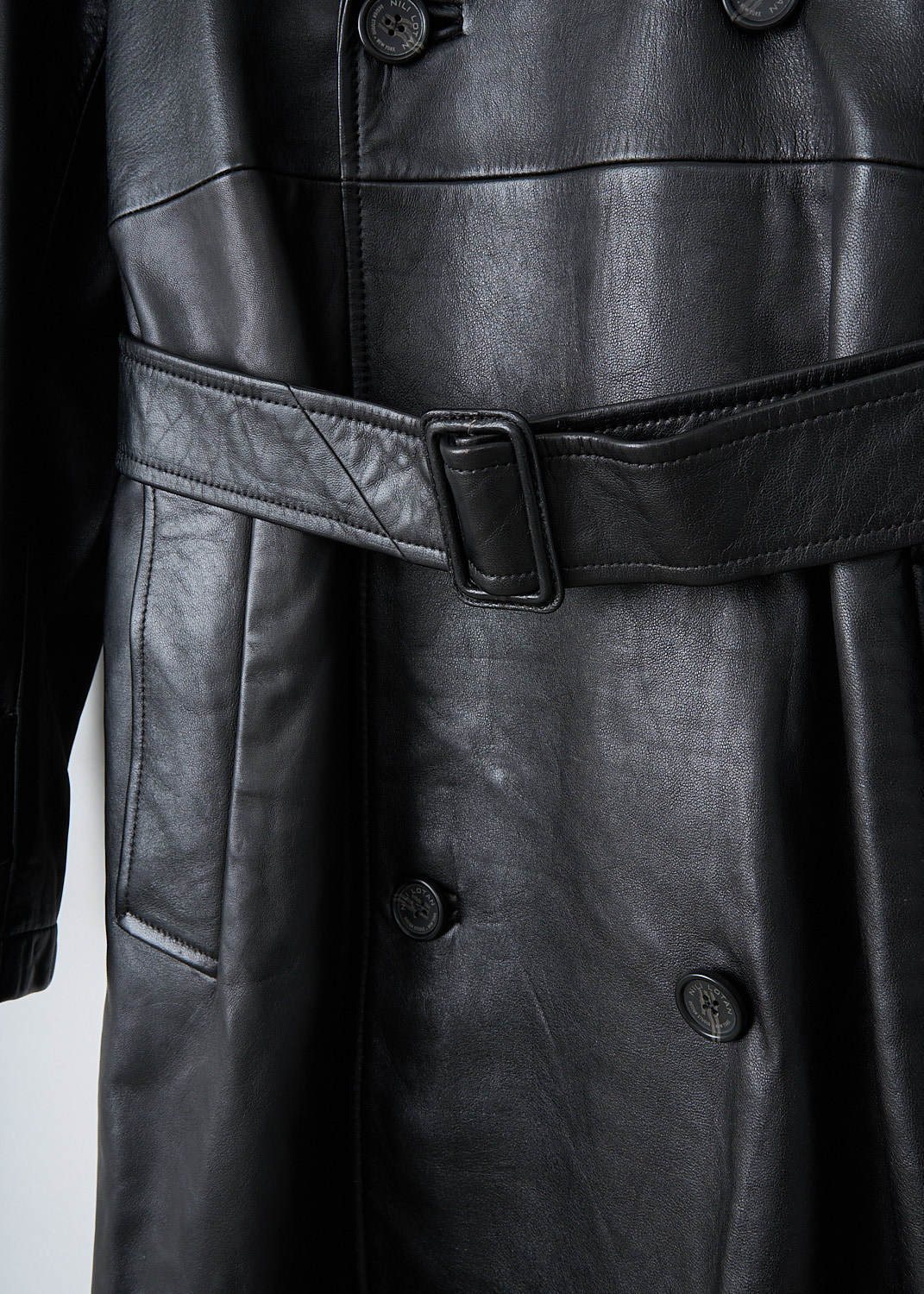 Nili Lotan, Peter oversized leather trench, PETER_OVERSIZED_LEATHER_TRENCH_12369_L115_BLK, Black, Detail, This Peter oversized leather trench has a notched lapel and a double-breasted front button closure. The coat has epaulettes on the shoulders. The long sleeves have cuff straps. The coat has a belted waist, slanted pockets and a single inner pocket.
