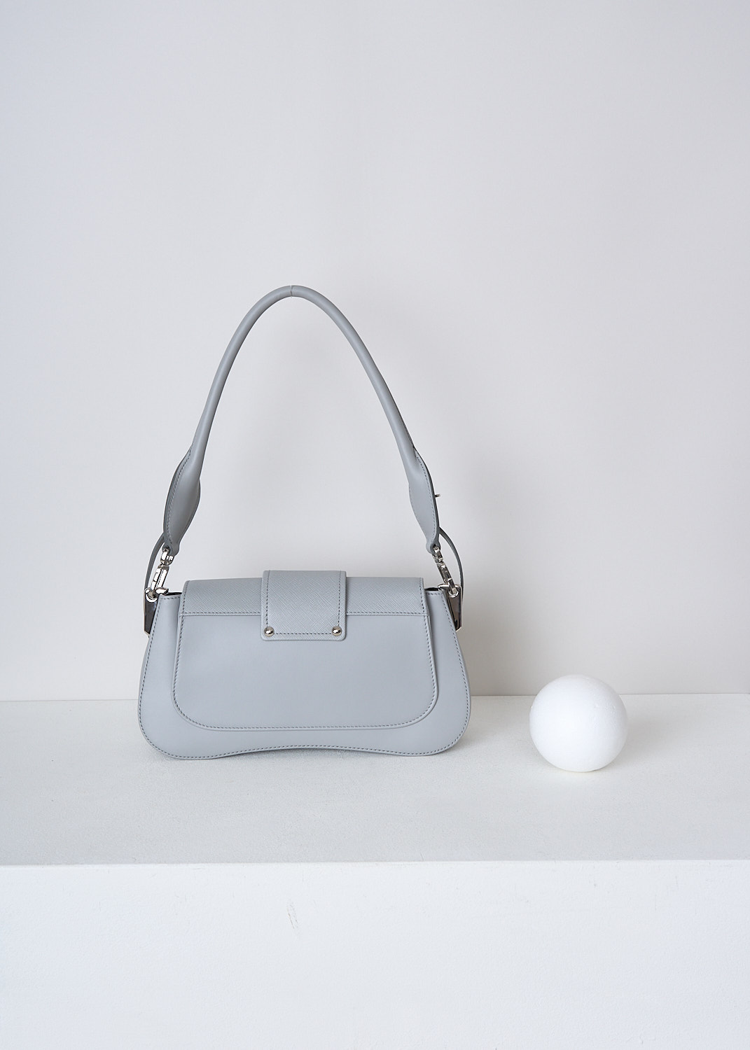 PRADA, SIDONIE SHOULDER BAG IN NUBE, 2BB0_CITY_CALF_SAFFI_1BD228_F0424_NUBE, Grey, Back, This Sidonie shoulder bag in the color Nube is made with both smooth and grained Saffiano leather. The bag comes witha detachable leather top handle with decorative leather straps and an adjustable and detachable shoulder strap. The bag has silver-tone metal hardware with the brand's logo on the front. The slip-through closure opens up to reveal the spacious compartment with a single patch pocket.  

