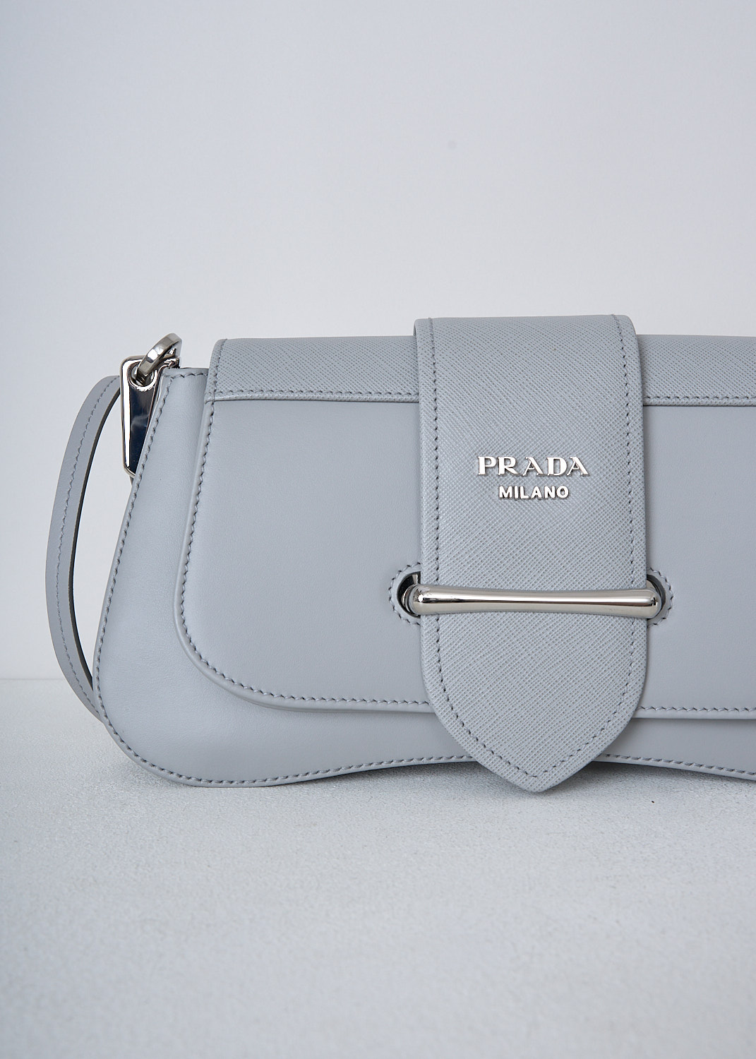 PRADA, SIDONIE SHOULDER BAG IN NUBE, 2BB0_CITY_CALF_SAFFI_1BD228_F0424_NUBE, Grey, Detail, This Sidonie shoulder bag in the color Nube is made with both smooth and grained Saffiano leather. The bag comes witha detachable leather top handle with decorative leather straps and an adjustable and detachable shoulder strap. The bag has silver-tone metal hardware with the brand's logo on the front. The slip-through closure opens up to reveal the spacious compartment with a single patch pocket.  

