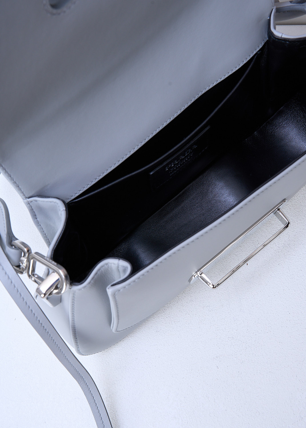 PRADA, SIDONIE SHOULDER BAG IN NUBE, 2BB0_CITY_CALF_SAFFI_1BD228_F0424_NUBE, Grey, Detail 1, This Sidonie shoulder bag in the color Nube is made with both smooth and grained Saffiano leather. The bag comes witha detachable leather top handle with decorative leather straps and an adjustable and detachable shoulder strap. The bag has silver-tone metal hardware with the brand's logo on the front. The slip-through closure opens up to reveal the spacious compartment with a single patch pocket.  

