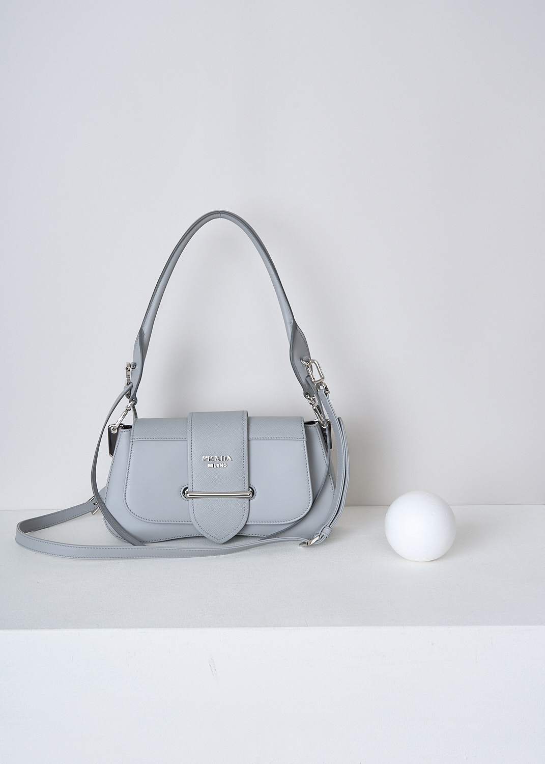 PRADA, SIDONIE SHOULDER BAG IN NUBE, 2BB0_CITY_CALF_SAFFI_1BD228_F0424_NUBE, Grey, Front, This Sidonie shoulder bag in the color Nube is made with both smooth and grained Saffiano leather. The bag comes witha detachable leather top handle with decorative leather straps and an adjustable and detachable shoulder strap. The bag has silver-tone metal hardware with the brand's logo on the front. The slip-through closure opens up to reveal the spacious compartment with a single patch pocket.  

