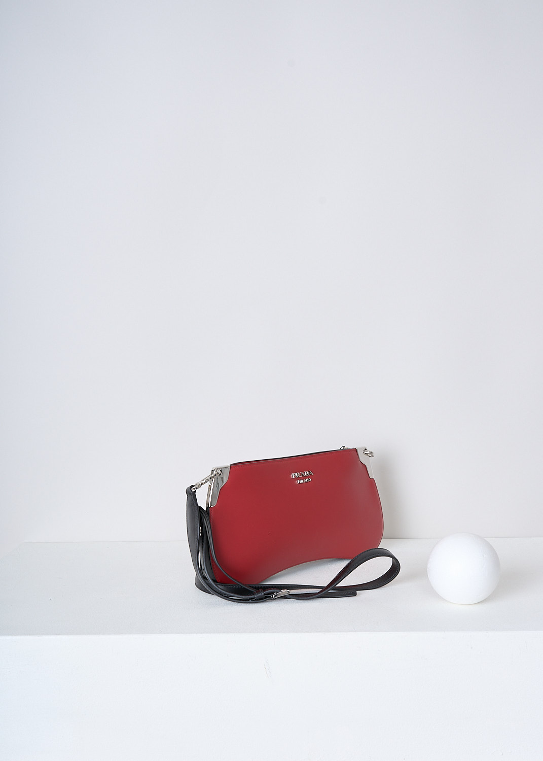 PRADA, BRIGHT RED CROSSBODY BAGUETTE BAG, 2AIX_CITY_CALF_1BH111_F0C9F_FUOCO_NERO, Red, Side, This red leather baguette bag has silver-tone hardware with the brand's lettering on the front in silver-tone metal. The bag has a zip closure that opens up to the main compartment. The compartment has a single slit pocket. The bag has a detachable black leather cross body strap which is adjustable in length. 

