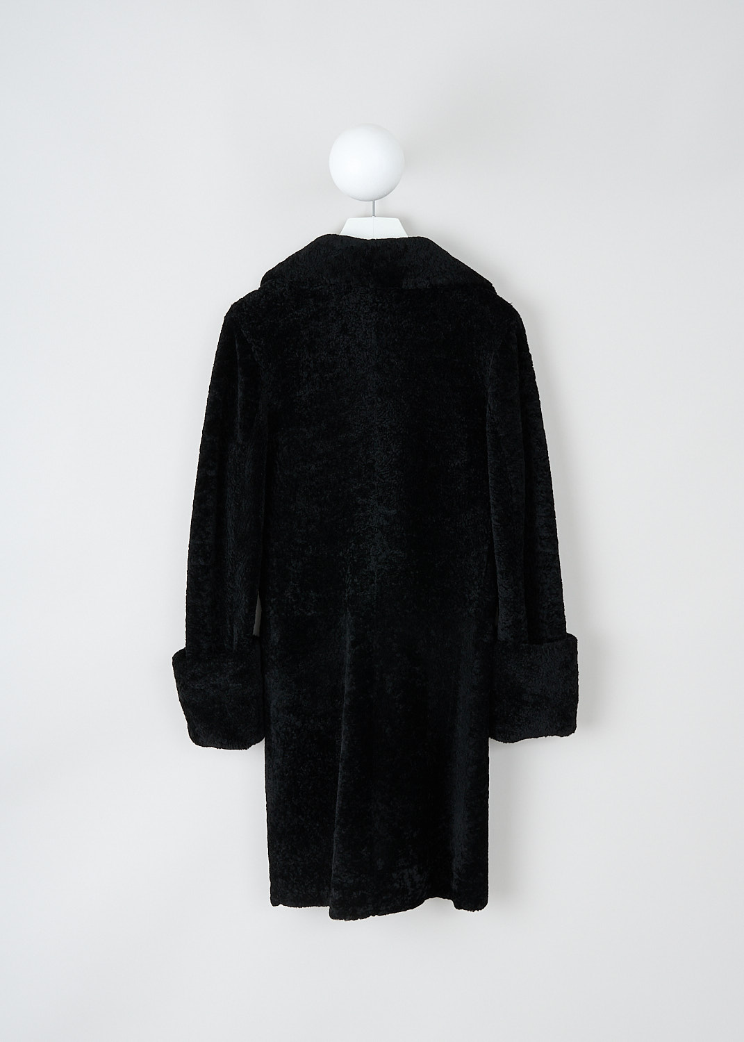 Prada, Black lammy coat with ribbon closure, 1XM2_MONTONE_56950_F0002_NERO, Black, Back, This black lammy coat has an exaggerated notched lapel. To one side, a black grosgrain ribbon functions as the closure. The closure is supported by a concealed button on the inside. The long sleeves have broad folded cuffs. In the front, the coat has patch pockets with decorative flaps. The coat has a straight hemline.  
