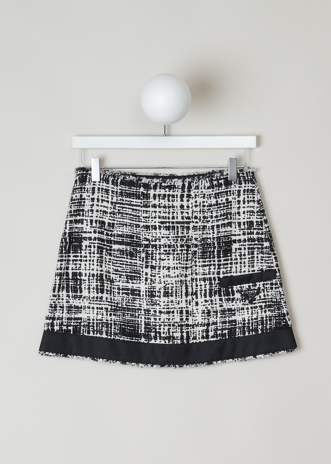 PRADA, BLACK AND WHITE TWEED MINI SKIRT, P164T_F0A72_03_TELONE_TWEED_RE_AVORIO_NERO, Black, White, Print, Back, This black and white tweed mini skirt has a concealed zip closure in the side seam. The skirt has a broad black trim along the hemline. In the back, the skirt has a single welt pocket with a black trim with underneath a black and silver logo plaque. The skirt is fully lined. 
