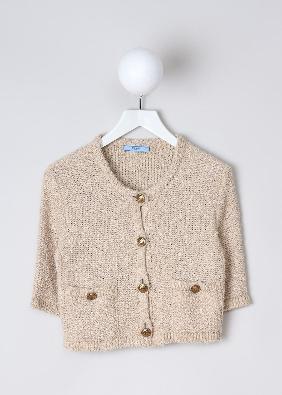 PRADA, SILK BOUCLÉ CARDIGAN IN NATURAL, P25L72_12ZD_F0018_NATURALE_, Beige, Front, This beige silk bouclé cardigan has a round neckline and a front button closure with embossed gold-tone buttons. The cardigan has three-quarter sleeves. On the front, the cardigan has two patch pockets with those same embossed buttons. The cardigan has a cropped length. In the back, a logo patch can be found. 
