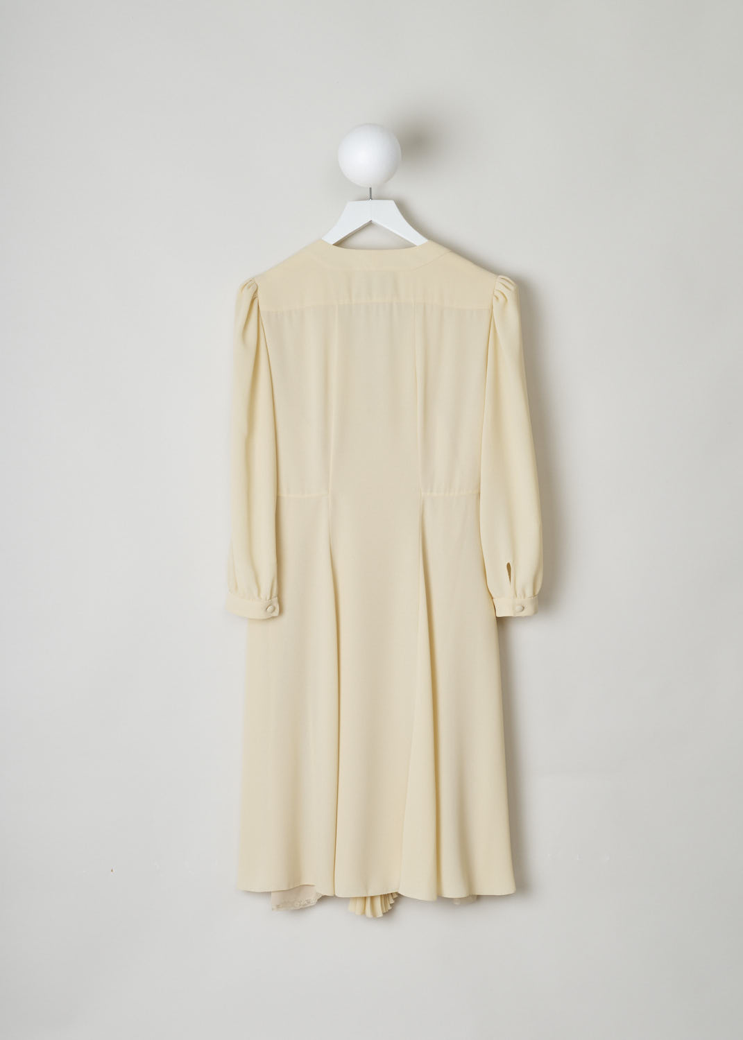 PRADA, CREAM COLORED DRESS WITH V-NECKLINE, SABLE_LEGGRO_P39W5_1WBZF0061_CREMA, Beige, Back, This feminine silk dress is made in a nude color. The dress has a plunging V-neck with on the bust a row of Dorset buttons. The dress has long sleeves with gathered shoulders. A single Dorset button can also be found on the cuffs. This dress has an empire-style waistline with on the skirt portion, a strip of accordion pleats. A concealed side zipper functions as the closure option. The dress comes with a matching nude slip dress with lace detailing.
