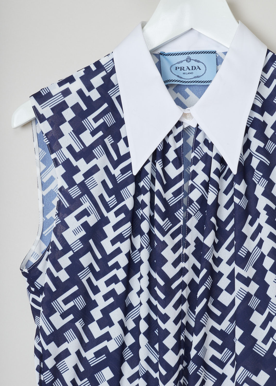 Prada, Geometric print blouse dress in blue and white, sable_leg_patte_P3A91H_F0PLR_baltico_bianco, blue white, detail, Sleeveless model featuring a pointed collar and two belt loops on the sides with a black velvet belt decorated with two ivory colored buttons. Going further down the skirt has accordion pleats and the concealed zipper is on the side. 