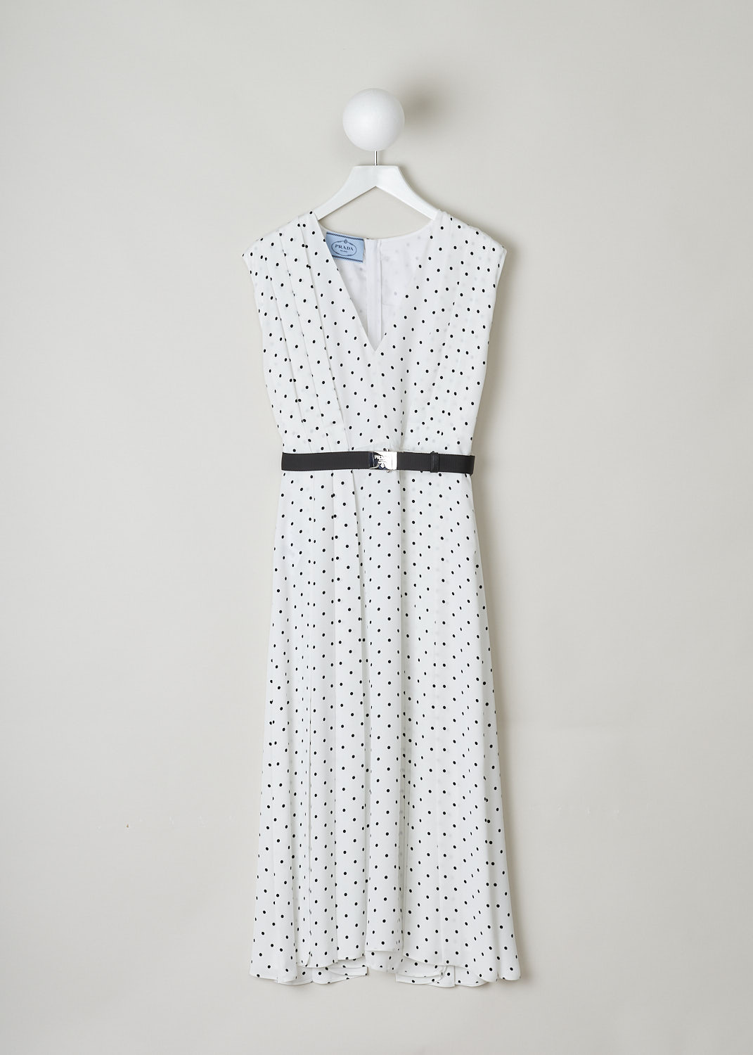 PRADA, WHITE POLKA-DOT MIDI DRESS WITH BELT, TWILL_FLUIDO_PO_P3D12H_F0A72_AVORIO_NERO, Black, White, Print, Front, This sleeveless silk dress has a white base with a black polka-dot print. The bodice has a V-neckline and pleats that go down into the skirt. A black canvas belt with a silver buckle can be used to cinch in the waist. A concealed centre zip in the back functions as the closure option. The dress comes with a detachable slip dress. 
