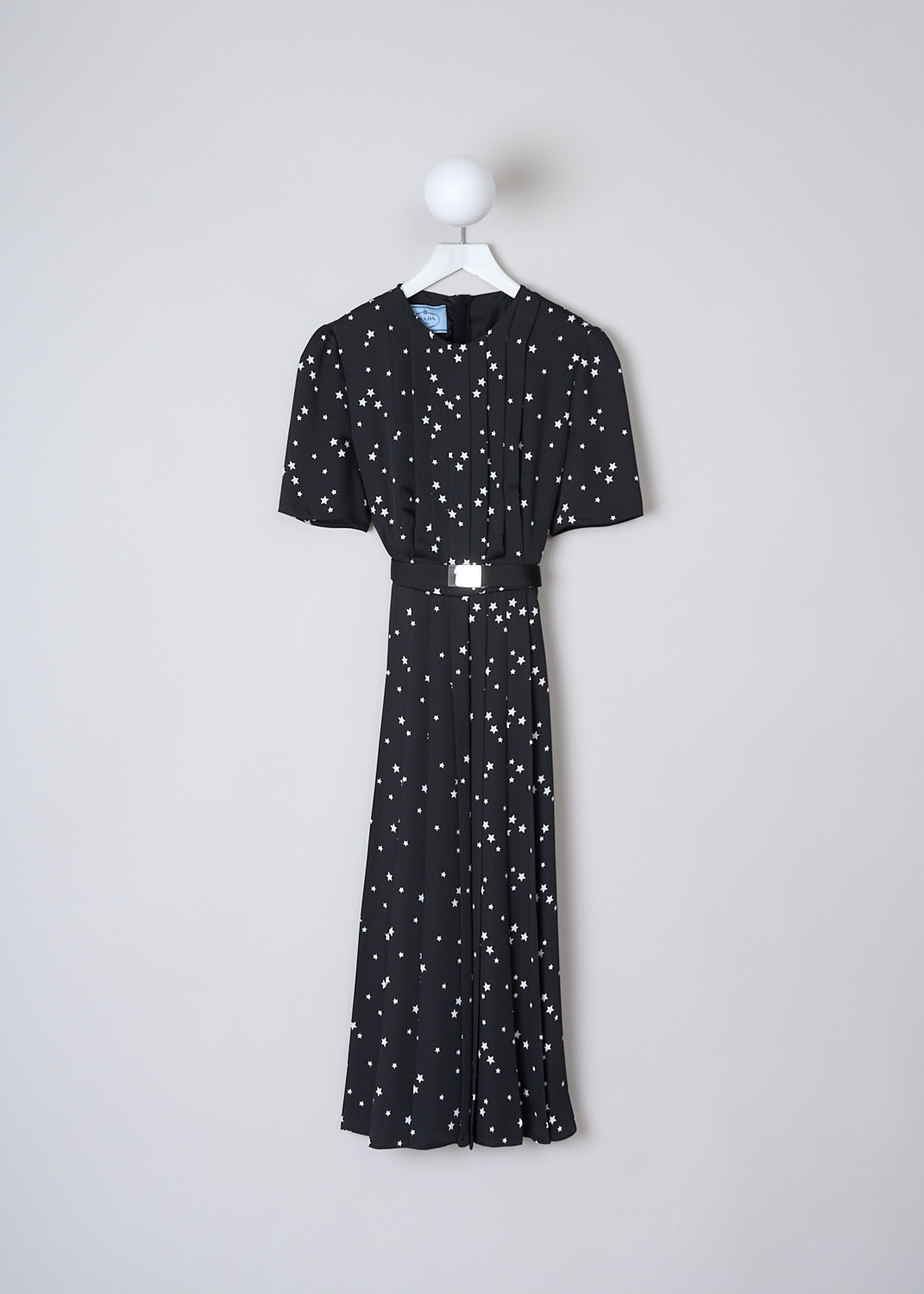 PRADA, BLACK MIDI DRESS WITH WHITE STAR PRINT, TWILL_FLUIDO_ST_P3D13H_1YH8_F057Z_NERO_AVORIO, Black, White, Print, Front, This black dress with a white all-over star print has a high round neckline and short sleeves. The dress has a knife-pleated bodice and is divided from the skirt through a black cavas belt with a rectangular silver-tone belt buckle with the brands logo on it. The dress has a flared pleated midi skirt. In the back, a concealed centre zip functions as the closure.   
