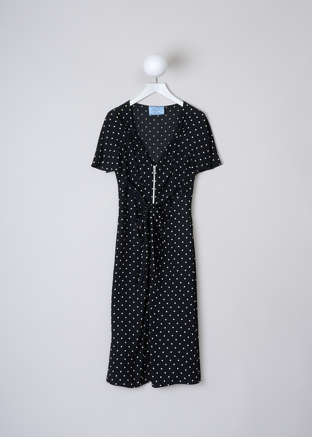 PRADA, BLACK MIDI DRESS WITH WHITE POLKA DOT PRINT, SABLE_POIS_ABITO_P3D14_1YH2_F057Z,  Black, White, Print, Front, This short sleeve midi dress has a black base color with a small white polka dot print. The dress has a V-neckline. In the front, a two-way zip runs down the length of the dress with gathered pleats along the zipper. Below the buste, two ties can be used to cinch in the dress. The dress has a straight hemline.


