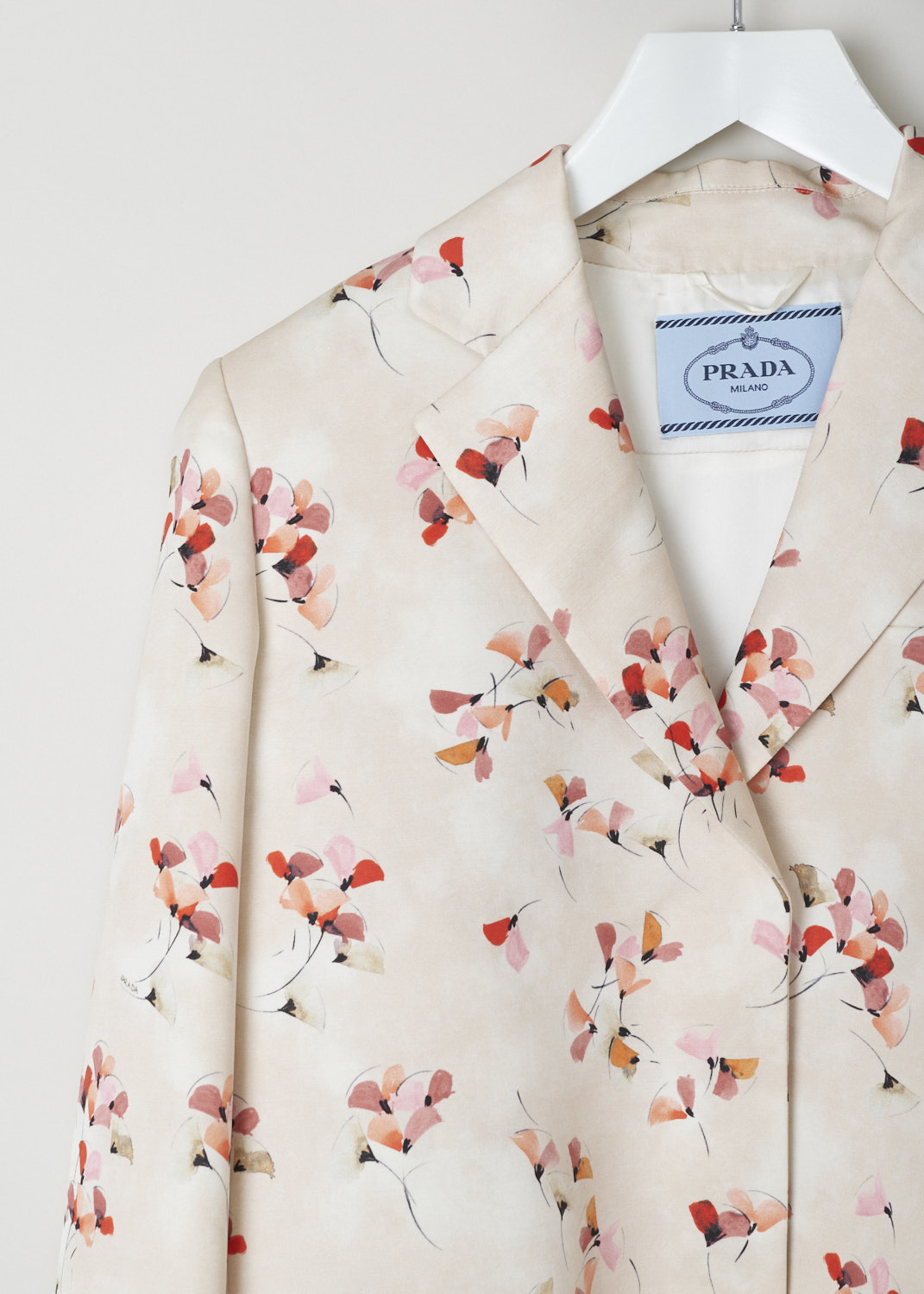 Prada, Peach coloured blazer adorned with a floral motif, radzmire_ginko_P5851_F0036_sabbia, pink red orange beige black print, detail, A cropped blazer comes coloured in a lighter shade of peach, and is decorated with an all over floral print in red, orange and beige. Further adorning the front is a notched lapel that leads into the fastening option being press studs, going further down there are two flap pockets on waist height and a single pocket on chest height. On the back you will find a deep inverted pleat on each of the shoulders ensures a unique fitting.