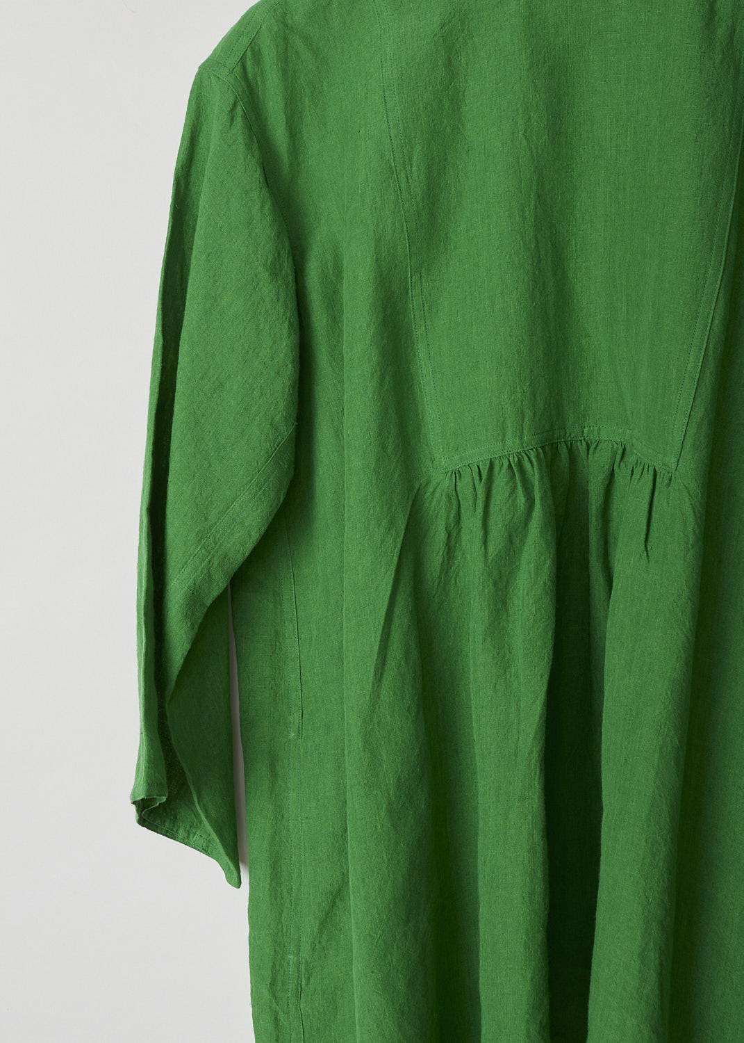 SOFIE Dâ€™HOORE, BRIGHT GREEN BINETTE TOP, BINETTE_LIFE_GRASS, Green, Detail, This oversized bright green top features a round neckline, dropped shoulders and long sleeves. The A-line top has a square bib-like front with pleated details below. Concealed in the side seams, slanted pockets can be found. The top has an asymmetrical finish, meaning the back is a little longer than the front. 


