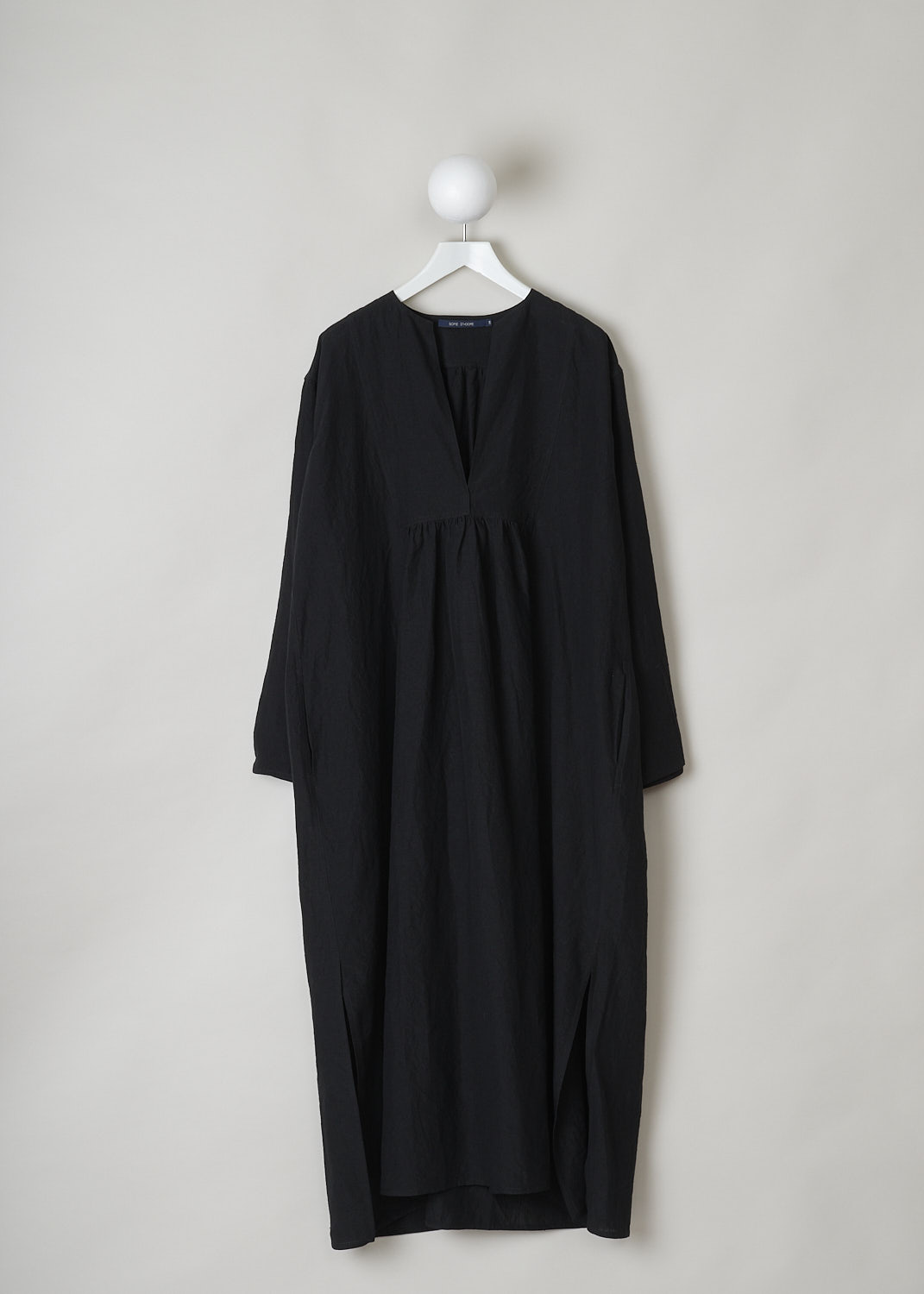 SOFIE D’HOORE, BLACK LINEN DELIZA DRESS, DELIZA_LIFE_BLACK, Black, Front,This black linen dress has a round neckline that goes into a deep V cutout. Subtle ruching can be found beneath the V. This long sleeve midi dress has a straight hemline with an asymmetrical finish, meaning the back is a little longer than the front. The dress has concealed slanted pockets and slits can be found on either side. The dress has a wide silhouette. 
