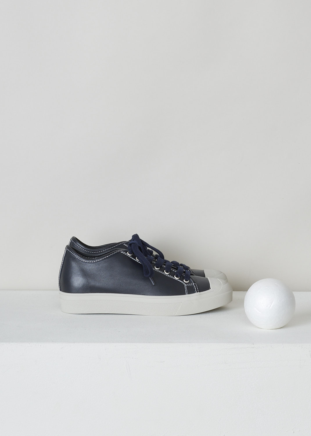SOFIE D’HOORE, MIDNIGHT BLUE LEATHER SHOES, FOLK_LMAST_LMAST_MIDNIGHT, Blue, Side, These midnight blue leather sneakers feature a front lace-up closure with dark blue laces. These sneakers have a round toe with a white rubber toe cap that goes down into the white rubber sole. Contrasting white stitching is used throughout. The sneakers come with additional pair of white laces.
