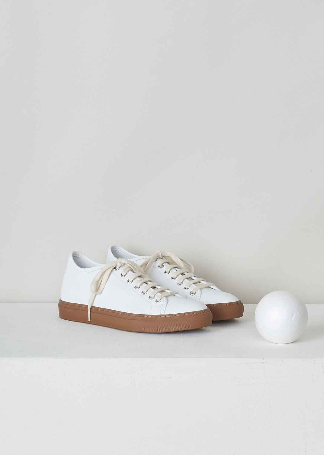 SOFIE D’HOORE, WHITE LEATHER SNEAKERS, FRIDA_LCOL_WHITE_CARAMEL, White, Brown, Front, These low-top white leather sneakers feature front lace-up fastening and a flat brown rubber sole. The sneakers come with additional pair of black laces.
