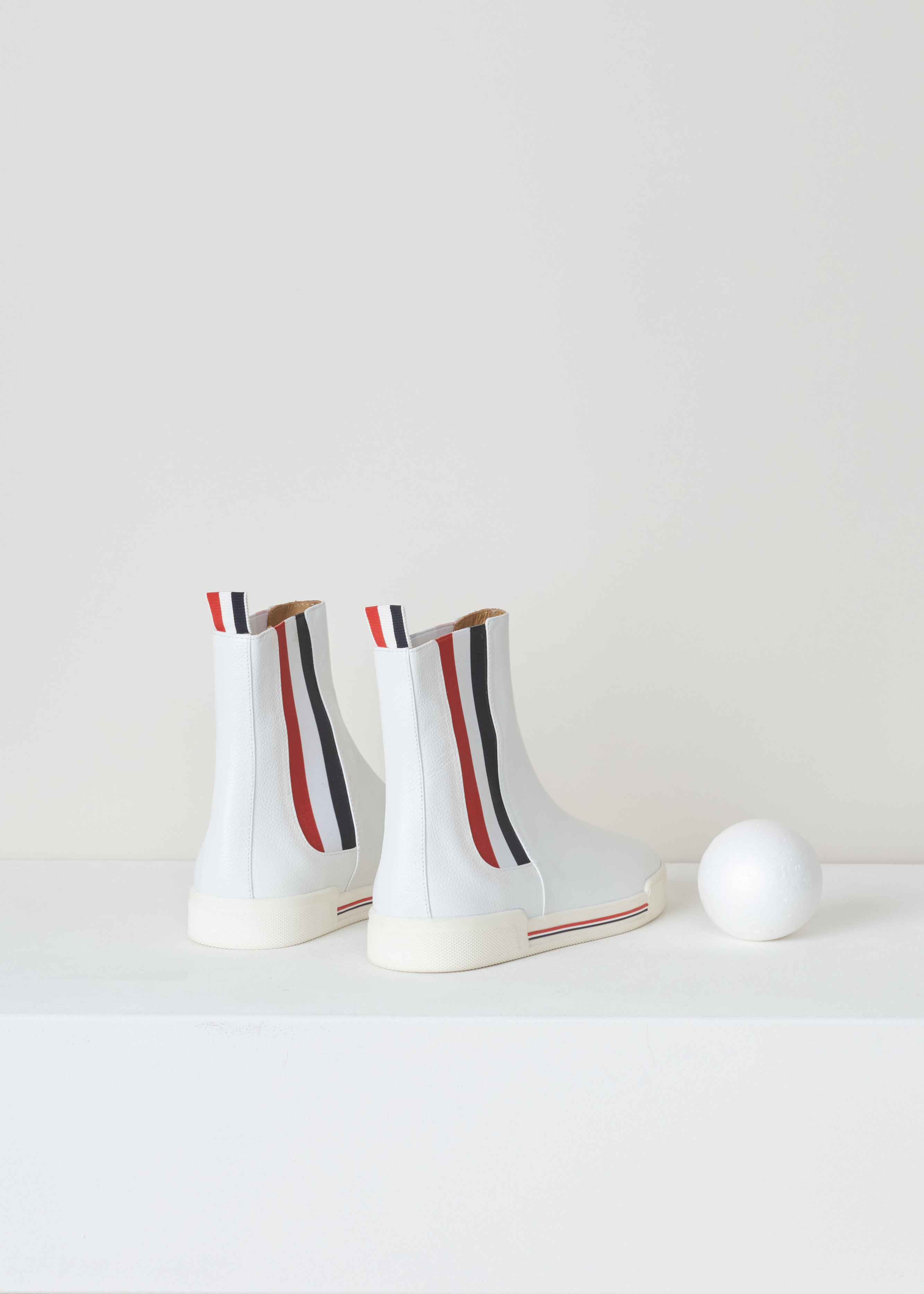 Thom Browne Chelsea boot sneaker white FFB056B_03542_100 white back. White leather chelsea boot with red and blue striped elastic side panels, a rounded toe, a pull tab at the back and a white rubber sole with red and blue detailing. 