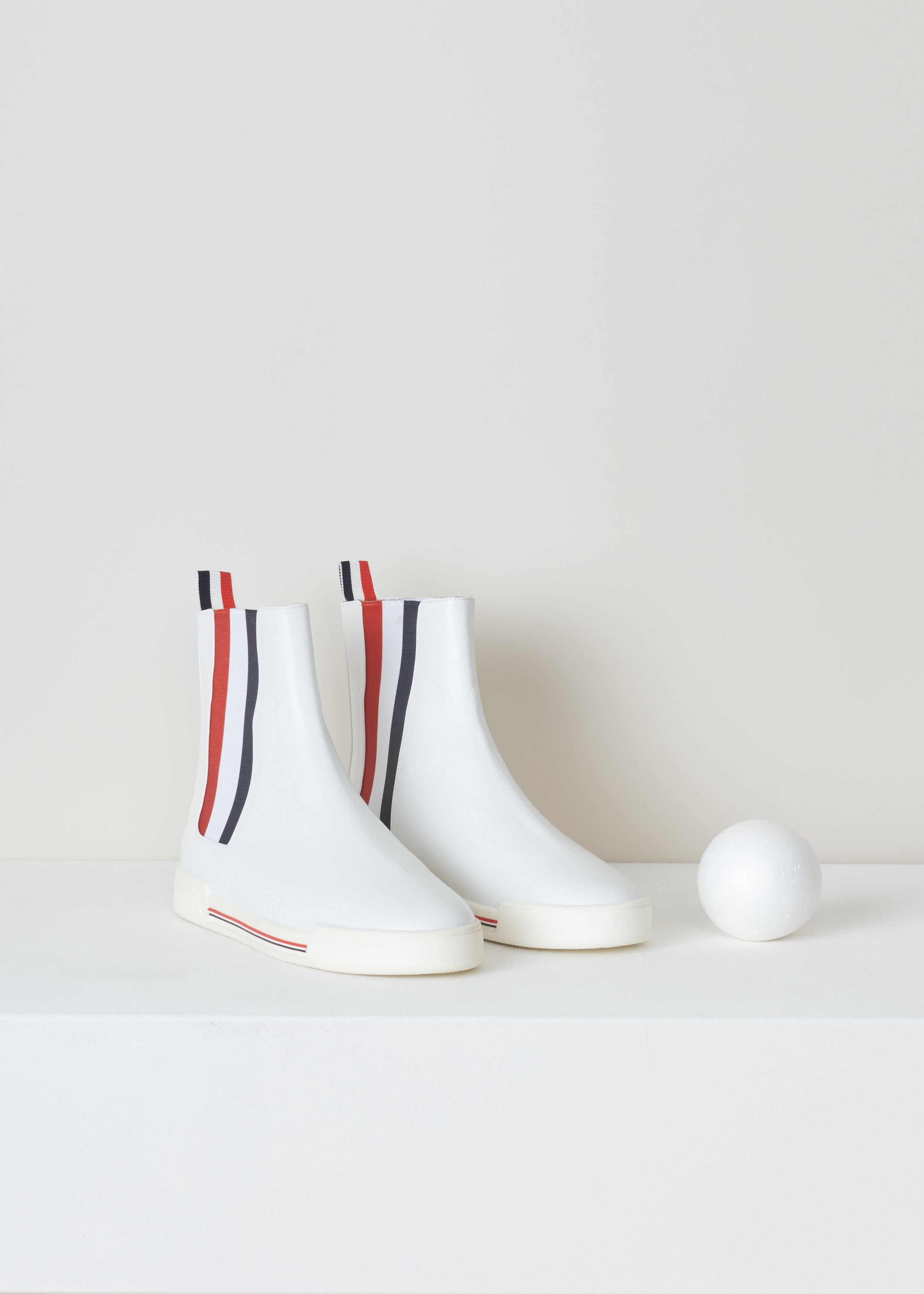 Thom Browne Chelsea boot sneaker white FFB056B_03542_100 white front. White leather chelsea boot with red and blue striped elastic side panels, a rounded toe, a pull tab at the back and a white rubber sole with red and blue detailing. 