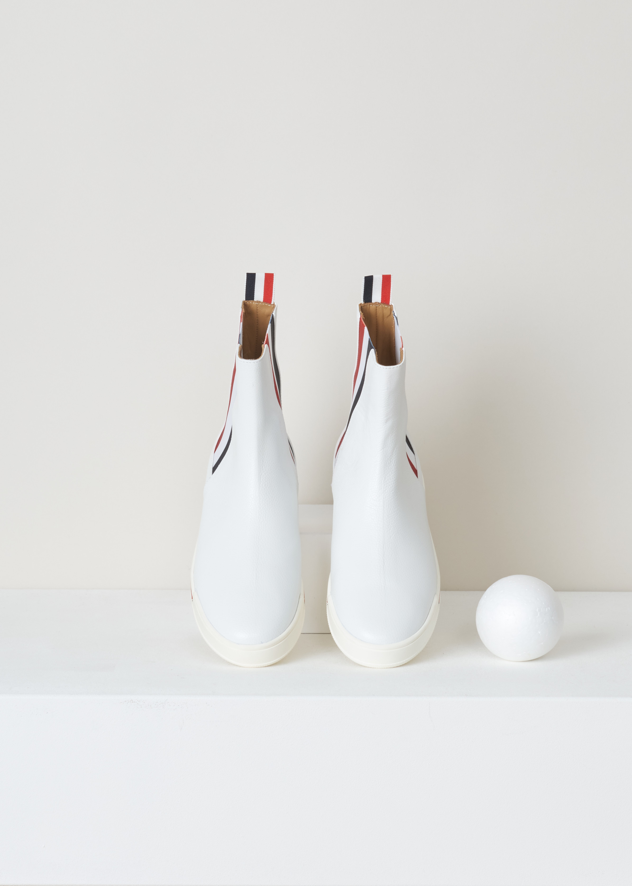 Thom Browne Chelsea boot sneaker white FFB056B_03542_100 white top. White leather chelsea boot with red and blue striped elastic side panels, a rounded toe, a pull tab at the back and a white rubber sole with red and blue detailing. 