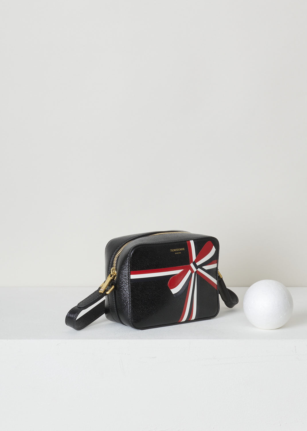 THOM BROWNE, CROSS BODY BAG WITH BOW DETAIL IN THE SIGNATURE TRI-COLOR STRIPE, FAP116A_03542_001, Black, Print, Side, Leather cross body bag with a bow detail in the signature tri-color grosgrain stripe in the front and a single tri-colored tab on the back. This model is made with pebble grain leather. Up top, a gold-toned zipper gives access to the interior of the bag. The bag opens up to a single spacious compartment with on one side, a single patch pocket against the back wall. 


Size: 17 cm x 13 cm x 7 cm / 6.6 inch x 5.1 inch x 2.7 inch 
