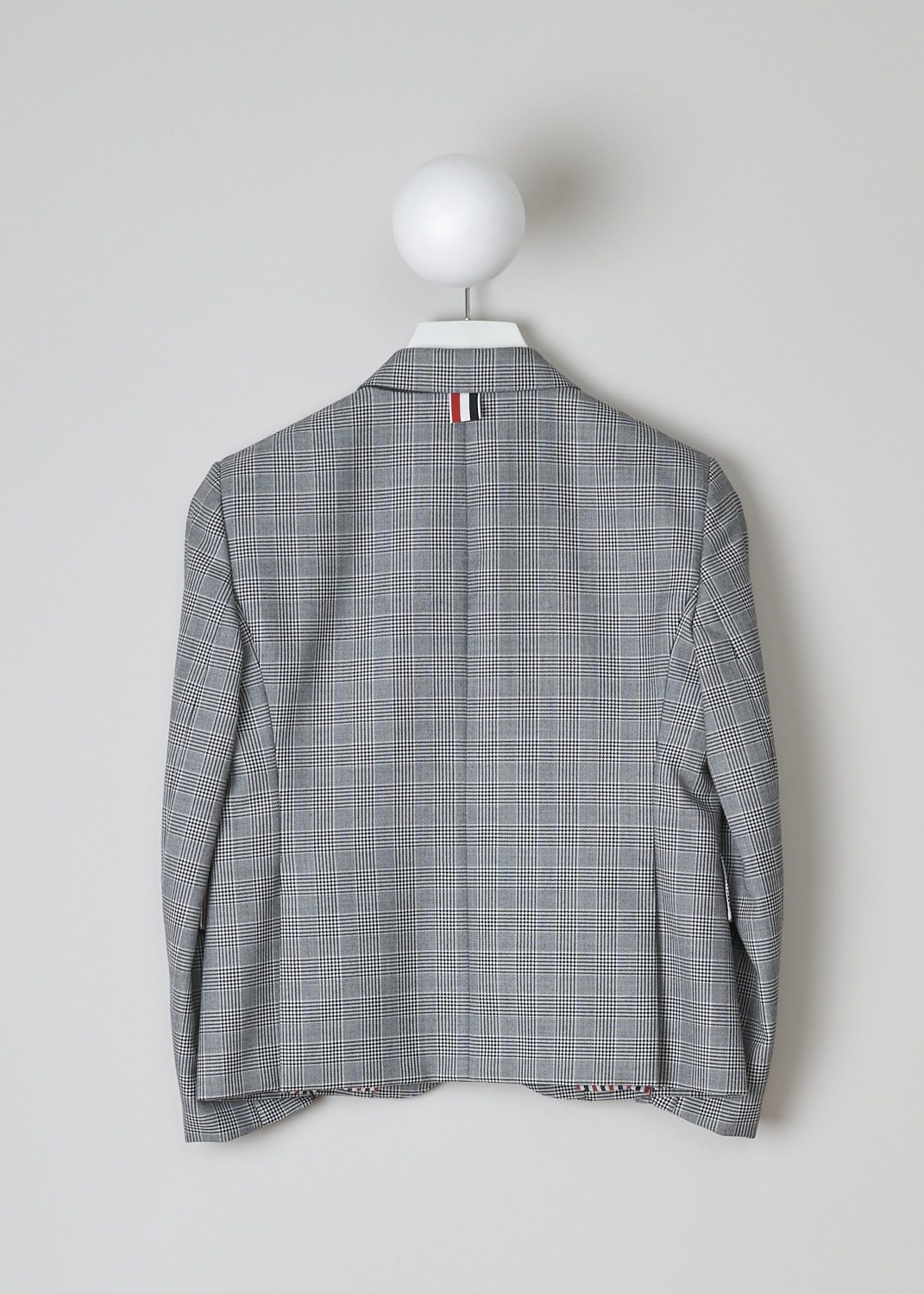 THOM BROWNE, BLACK AND WHITE CHECK SPORT JACKET, FBC010A_25057_980, Black, White, Back, This single-breasted sport jacket has a black and white houndstooth check motif. The jacket has a notched lapel and a front button closure. In the front, the jacket has a single breast pocket and two flap welt pockets. On the inside, the jacket has a striped lining, three inner pockets and a name tag. The brand's signature striped grosgrain loop tab can be found in the back. The jacket has a double vent.  
