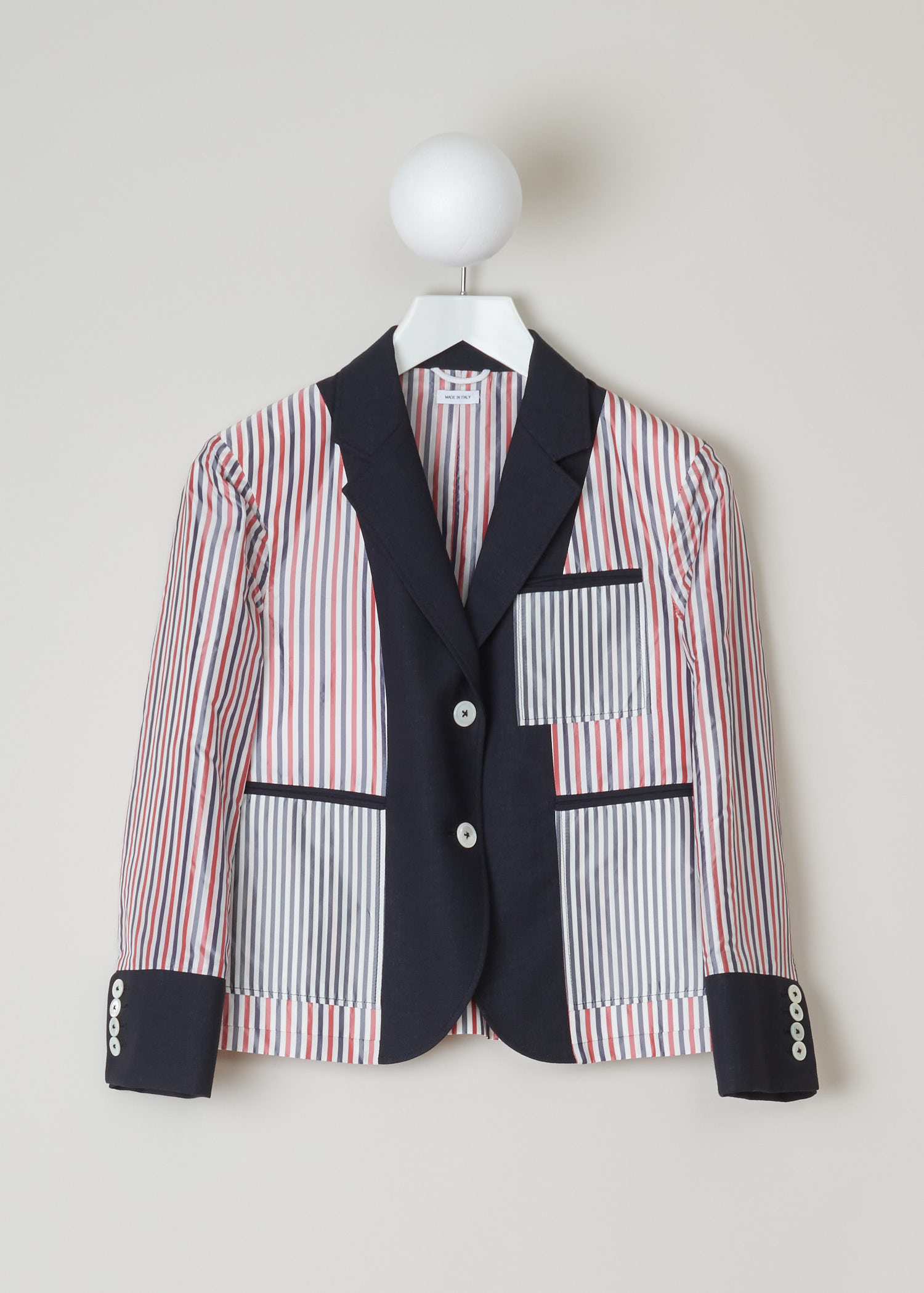 Thom Browne, Red and blue striped jacket, FBC510A_00473_415_navy, red white blue, front. This inside out jacket features a regular collar and a notched lapel. Going further down the long sleeves, you will find four buttoned cuffs. It has a single chest pocket and below that two jetted pockets. The jacket comes with the signature grosgrain  tab on the back.